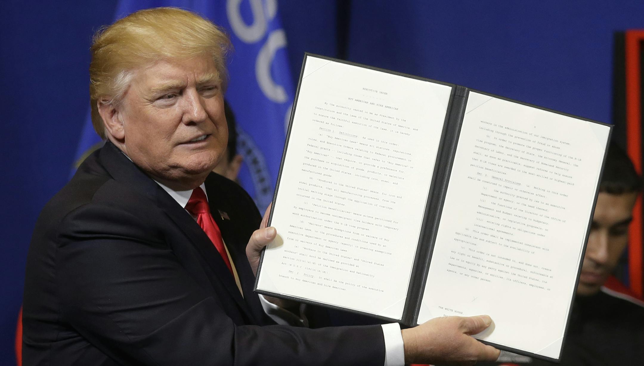 President Donald Trump holds up an executive order to tighten the rules for technology companies seeking to bring highly skilled foreign workers to the U.S., before signing, Tuesday, April 18, 2017, at Snap-On Tools in Kenosha, Wis. (AP Photo/Kiichiro Sato) ORG XMIT: MIN2017041911343626