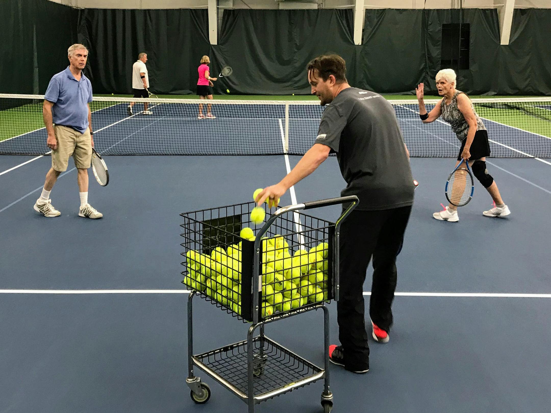 The Atterberrys and the Helgesons get coaching on their doubles game at Life Time's Oakdale Village Tennis club.