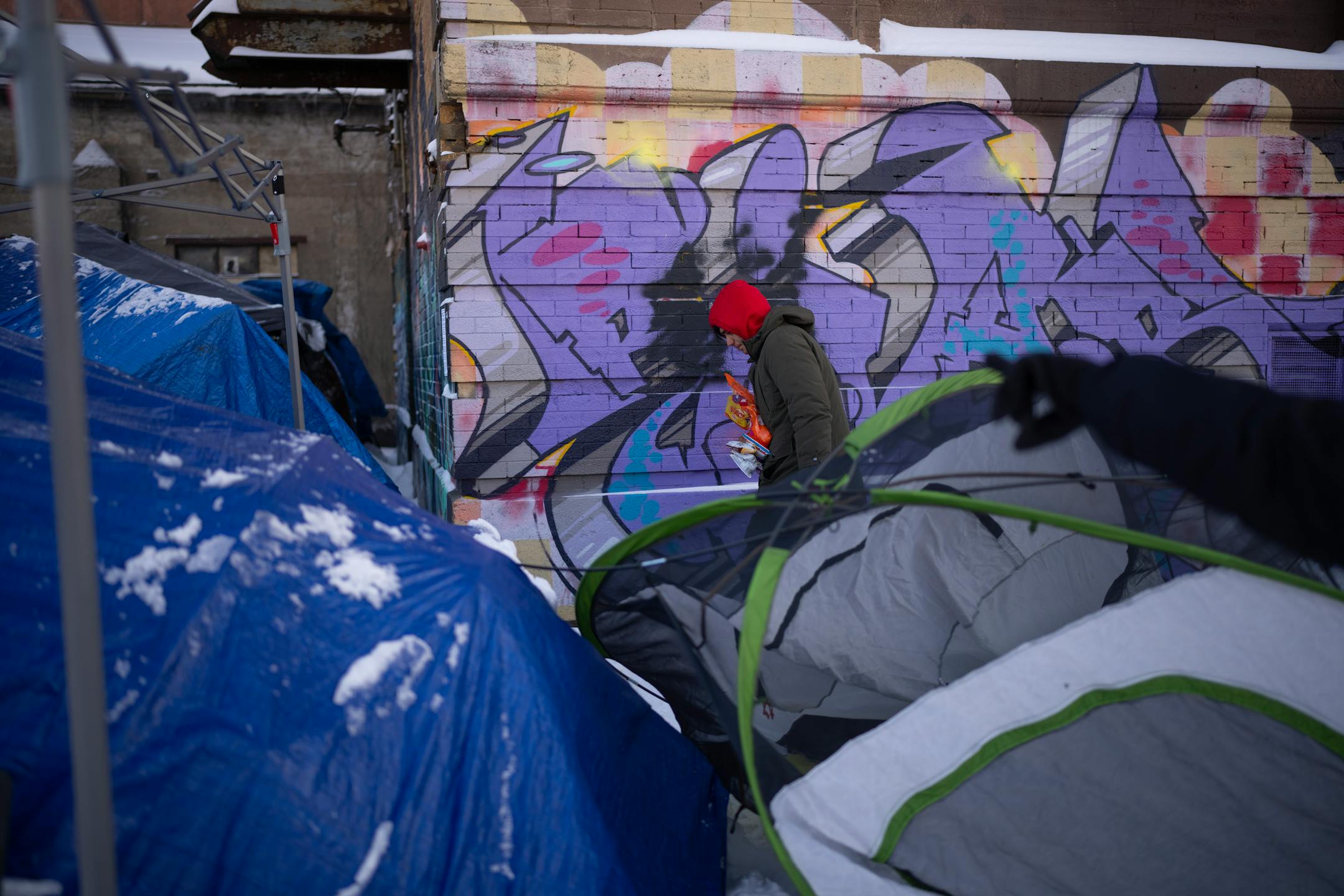 A young man living in an encampment along Hiawatha Ave. returned to his tent with a supply of hand warmers and snacks provided by outreach workers Dava Beaulieu and Leah Skjefte after they checked on the well being and offered hand warmers and snacks to residents there Thursday afternoon. Homeless outreach workers for the American Indian Community Development Corp. (AICDC), checked several homeless encampments to offer hand warmers and snacks or a ride to a shelter on a dangerously cold afternoon in Minneapolis Thursday, December 22, 2022.