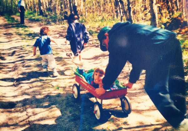 This vintage photograph shows the author riding in a wagon while her family walks through the woods near Clearwater Lake.