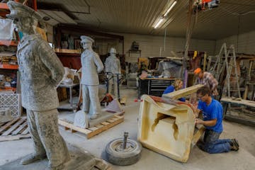 Dave and Shelly Speedling, foreground, and Pete Maringer reassemble a mold after unpacking a cement statute they poured of William R. Flores, a U.S. C