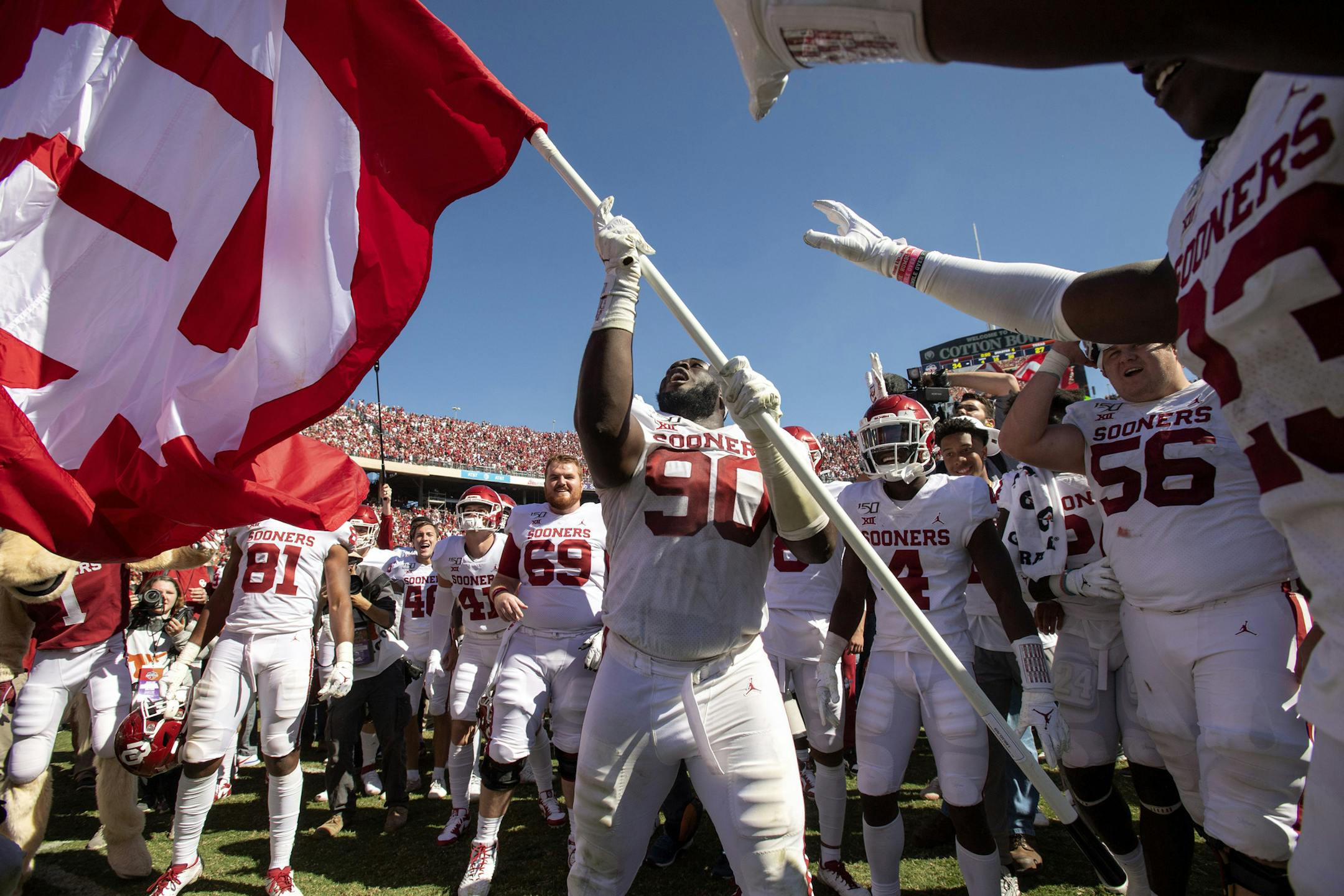 Oklahoma defensive lineman Neville Gallimore (90) waves an OU flag after his team's 34-27 victory over Texas in an NCAA college football game at the Cotton Bowl, Saturday, Oct. 12, 2019, in Dallas. (AP Photo/Jeffrey McWhorter)