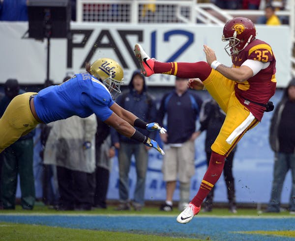UCLA linebacker Eric Kendricks, left, blocks a punt by Southern California's Kris Albarado during the second half of their NCAA college football game,