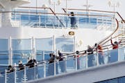 Passengers stand on the deck of the Diamond Princess cruise ship anchored at Yokohama Port in Yokohama, near Tokyo, Wednesday, Feb. 12, 2020. Japan&#x