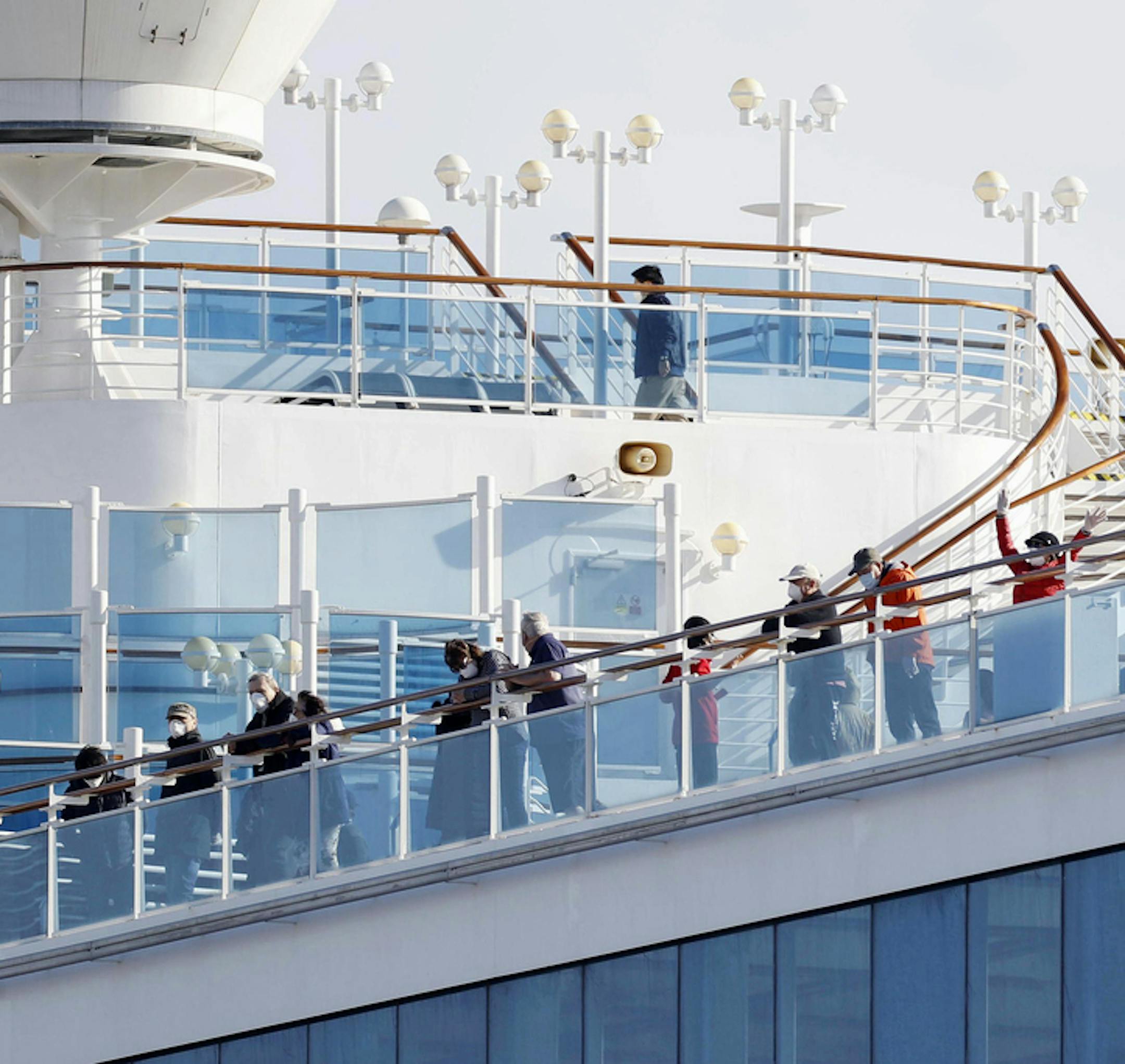 Passengers stand on the deck of the Diamond Princess cruise ship anchored at Yokohama Port in Yokohama, near Tokyo, Wednesday, Feb. 12, 2020. Japan’s health ministry said Wednesday that 39 new cases of a virus have been confirmed on the cruise ship quarantined at the Japanese port. (Yuta Omori/Kyodo News via AP)