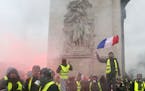 A demonstrator wearing a yellow jacket waves a French flag at the Arc de Triomphe during a demonstration Saturday, Dec.1, 2018 in Paris. Protesters an