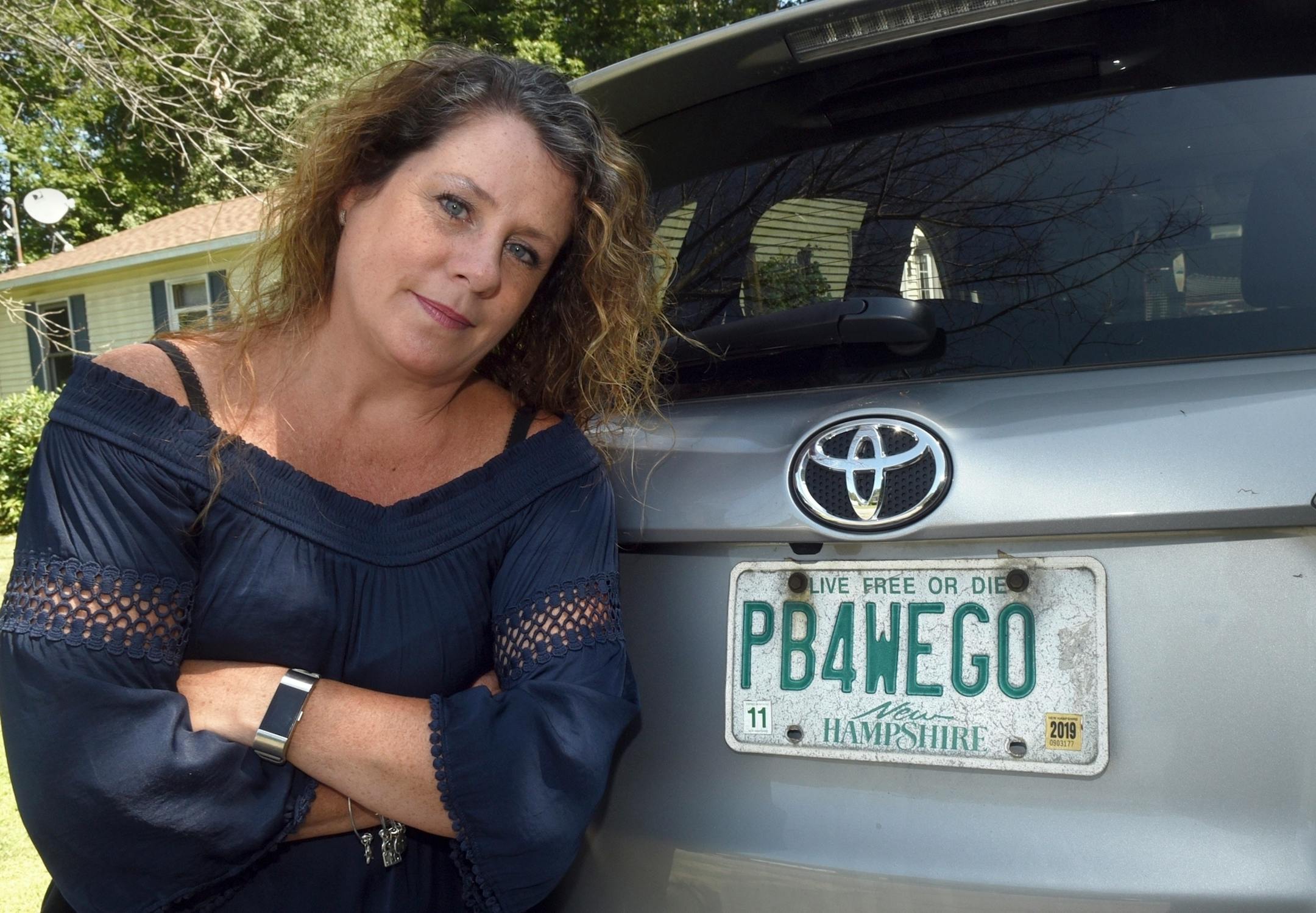 This Aug. 26, 2019 photo shows Wendy Auger standing by her vehicle in Rochester, N.H. The state Division of Motor Vehicles asked Auger to surrender the plate, which reads "PB4WEGO." The division said phrases related to excretory acts aren't permitted. Gov. Chris Sununu said Wednesday, Aug. 28, he reached out to the division and "strongly urged them" to allow Auger to keep the plate. Auger, who was appealing the recall, said "I'm stoked."/Foster's Daily Democrat via AP)