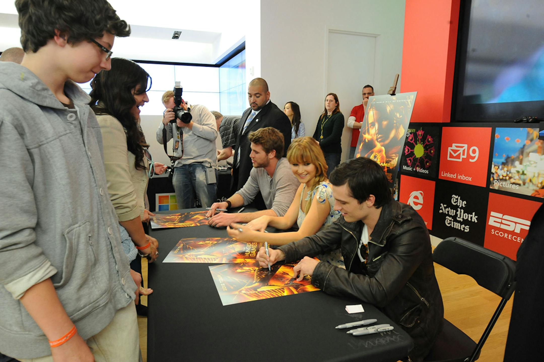 Liam Hemsworth, from left, Jennifer Lawrence, and Josh Hutcherson sign movie posters at "The Hunger Games," movie mall tour, Saturday, March 3, 2012, at The Westfield Mall in Century City, Calif.