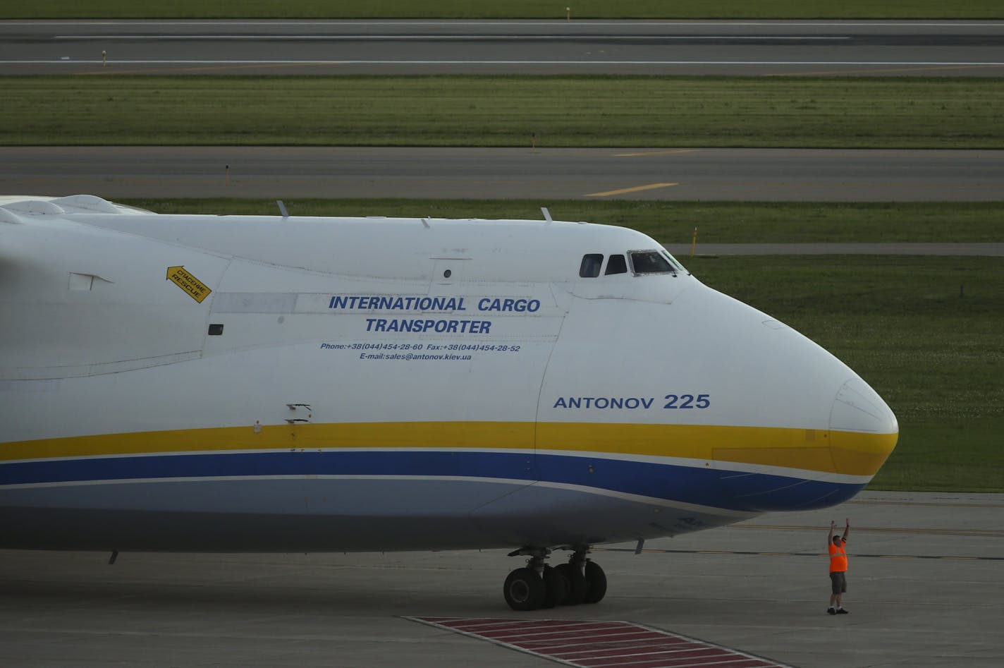 An airport ground crew member posed for a photo in front of the Antonov 225, the world's largest plane in service , as it was parked on the tarmac Monday evening.