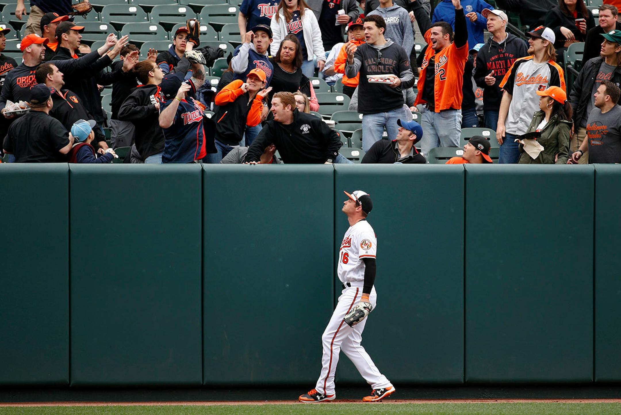 Baltimore Orioles left fielder Trey Mancini watches as fans clamor for a solo home run ball that was hit by Minnesota Twins' Brian Dozier in the first inning of a baseball game, Sunday, April 1, 2018, in Baltimore.