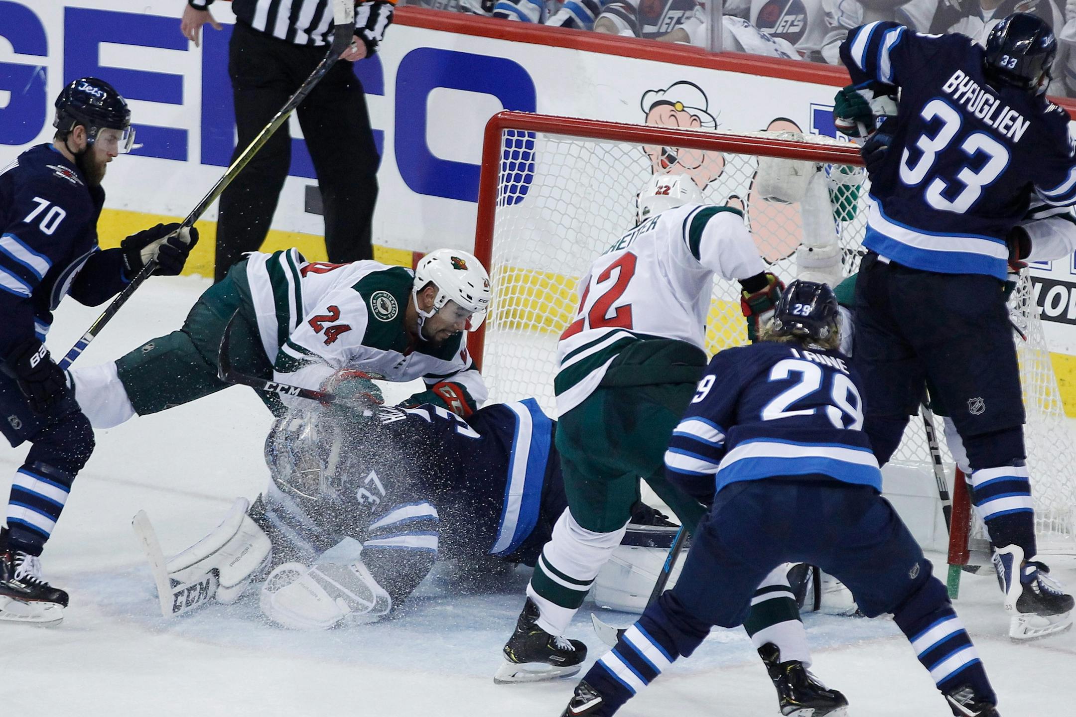Minnesota Wild's Matt Dumba (24) crashes into Winnipeg Jets goaltender Connor Hellebuyck (37) during the third period of Game 1 in an NHL hockey first-round playoff series Wednesday, April 11, 2018, in Winnipeg, Manitoba.