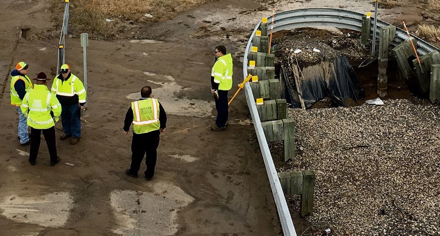 Workers and a state trooper size up the situation at the scene of a sinkhole along I-694 in Oakdale.