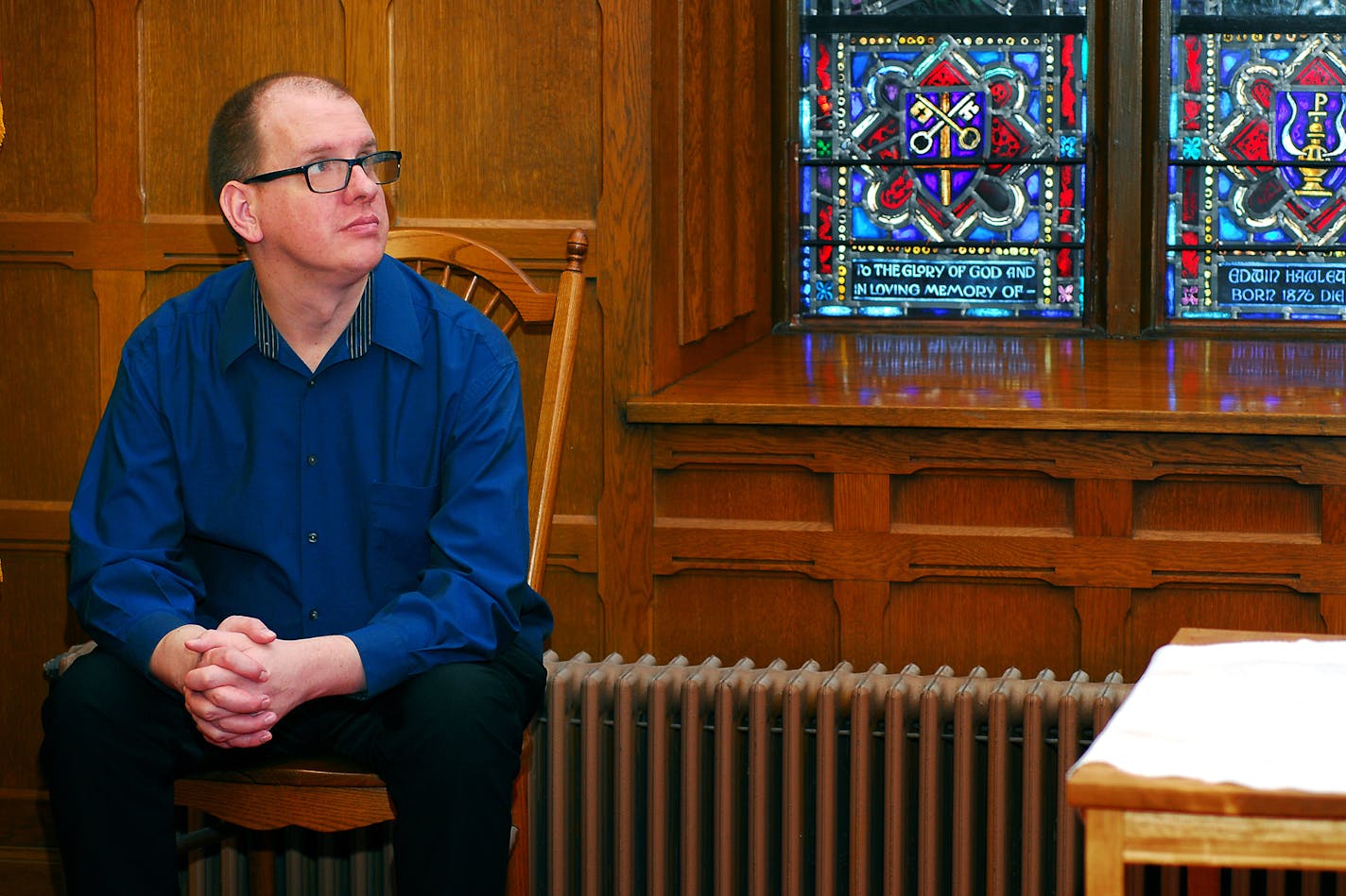 Portrait of Joe Bigalke in a church with stained glass windows.