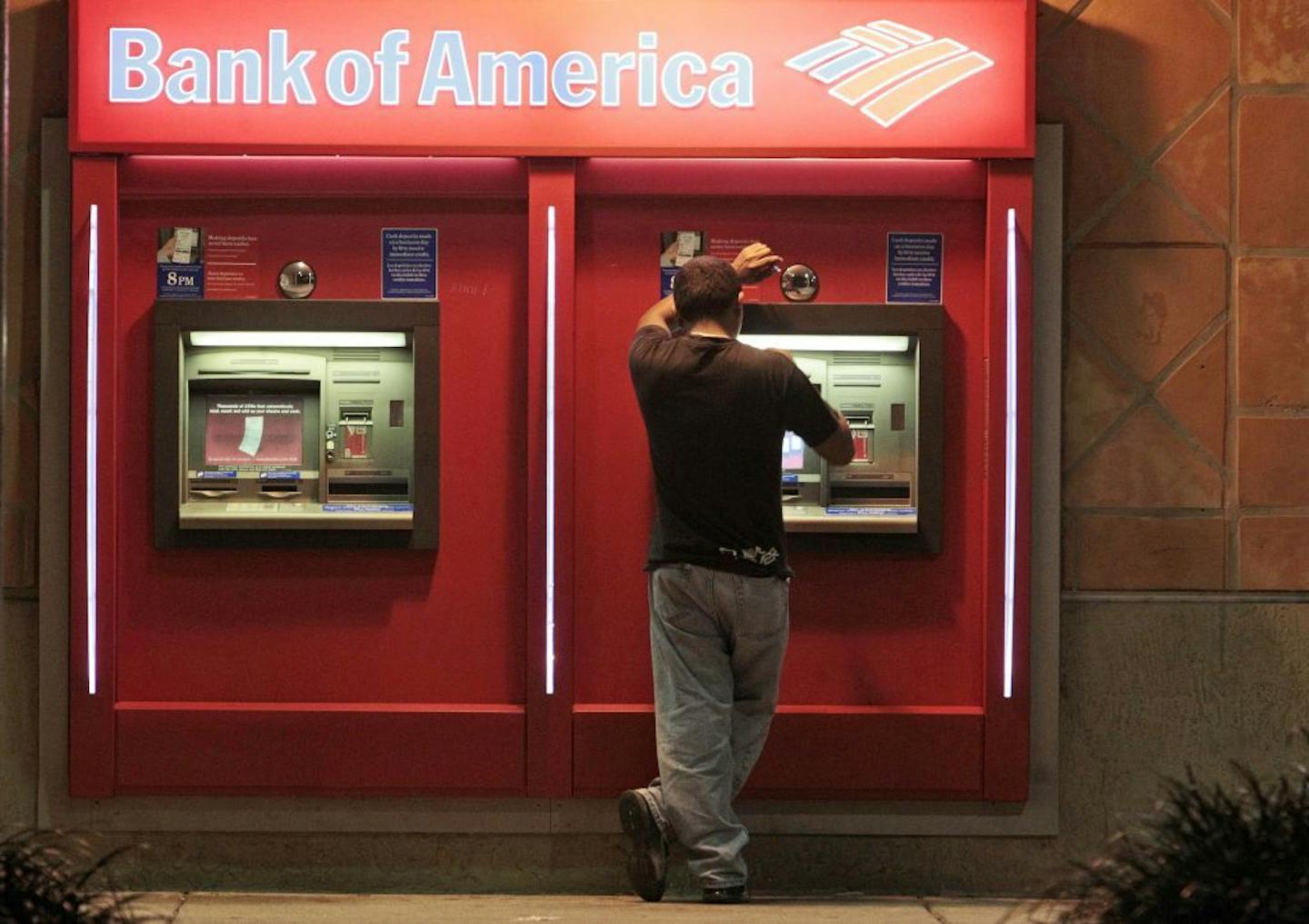 This photo taken Oct. 14, 2011, shows a customer at a Bank of America ATM in Hialeah, Fla.