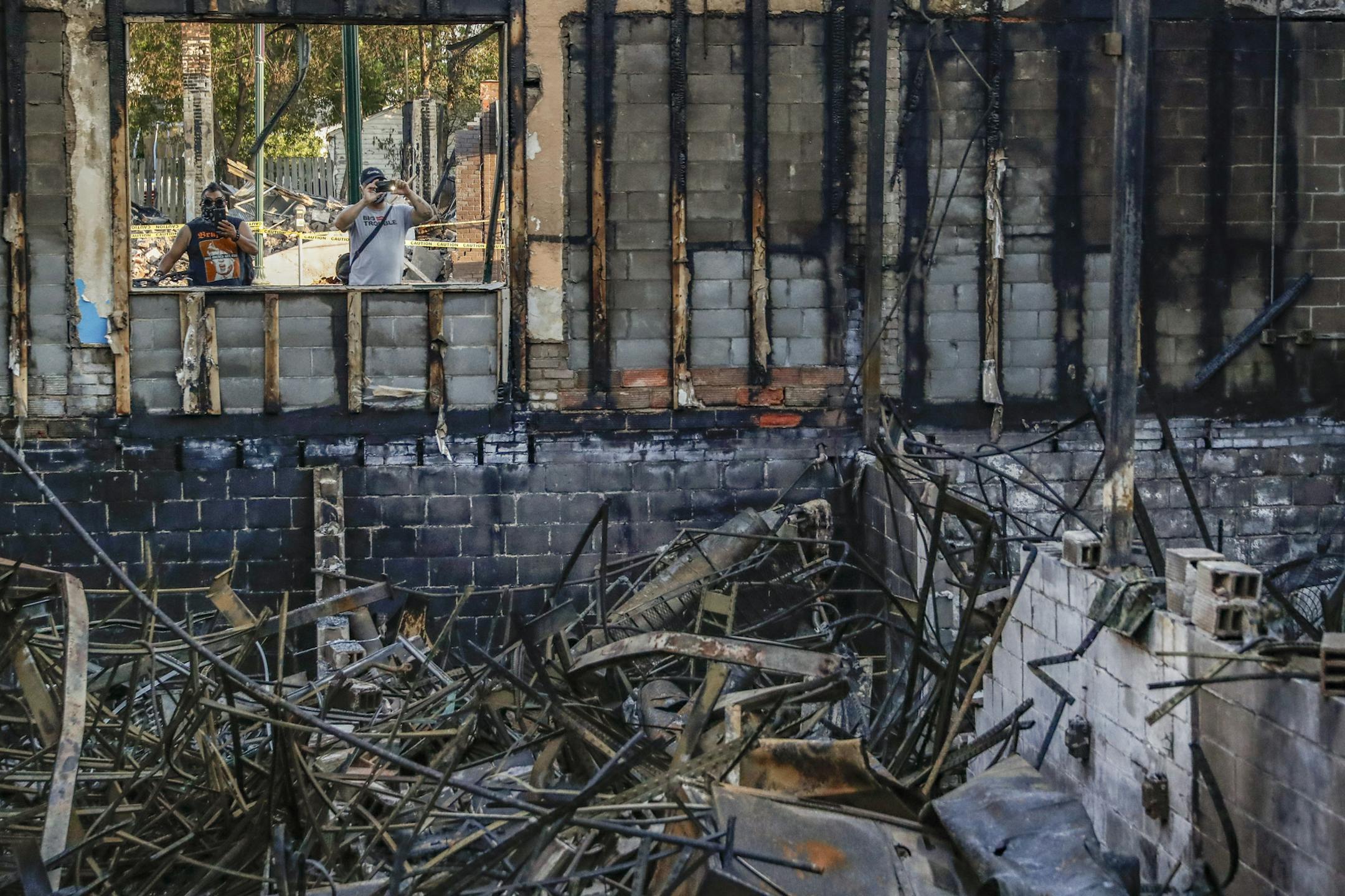 Pedestrians pass burned out businesses along East Lake Street destroyed in protesters two nights before, Monday, June 1, 2020, in Minneapolis. Protests continued following the death of George Floyd, who died after being restrained by Minneapolis police officers on Memorial Day. (AP Photo/John Minchillo)