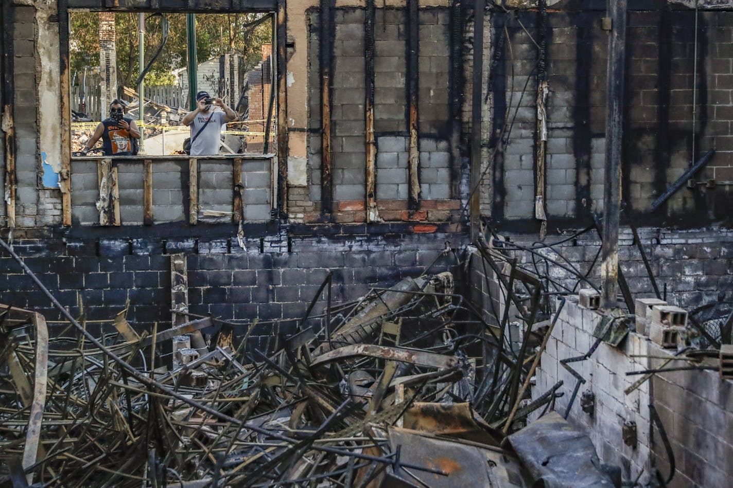 Pedestrians pass burned out businesses along East Lake Street destroyed in protesters two nights before, Monday, June 1, 2020, in Minneapolis. Protests continued following the death of George Floyd, who died after being restrained by Minneapolis police officers on Memorial Day. (AP Photo/John Minchillo)