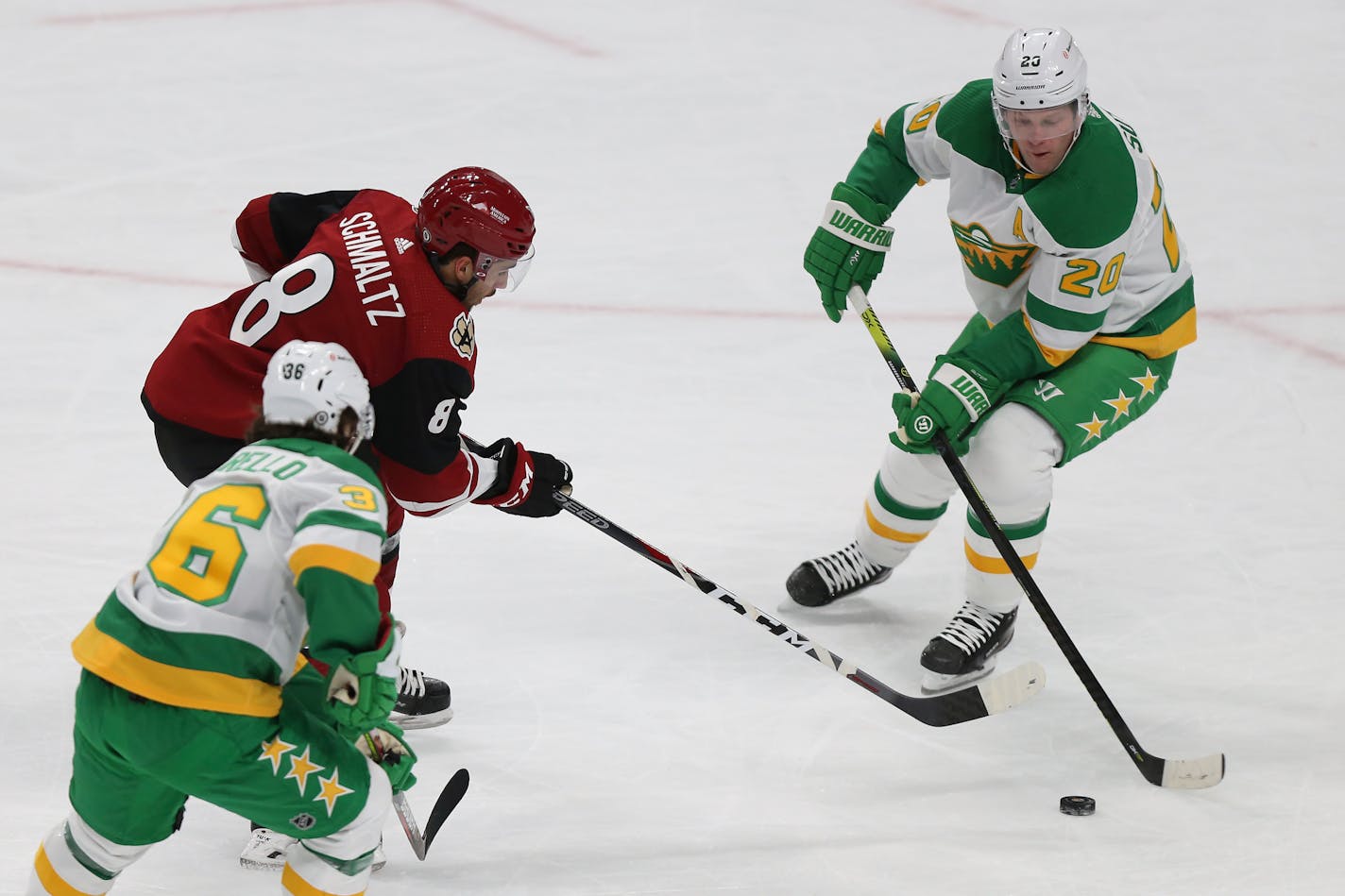 Minnesota Wild's Ryan Suter (20) tries to gain control of the puck against Arizona Coyotes' Nick Schmaltz (8) during the first period of an NHL hockey game Friday, March 12, 2021, in St. Paul, Minn. (AP Photo/Stacy Bengs)