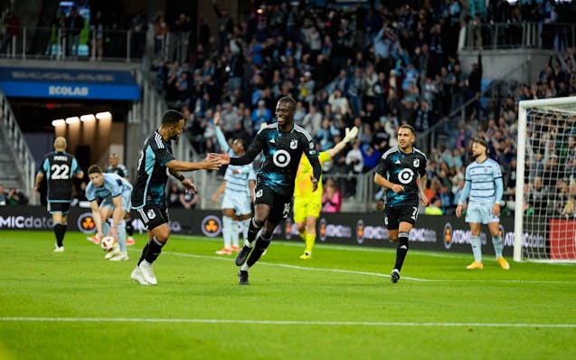 Minnesota United striker Tani Oluwaseyi, center, gets a high-five from  right wingback DJ Taylor after Oluwaseyi scored against Sporting Kansas City o
