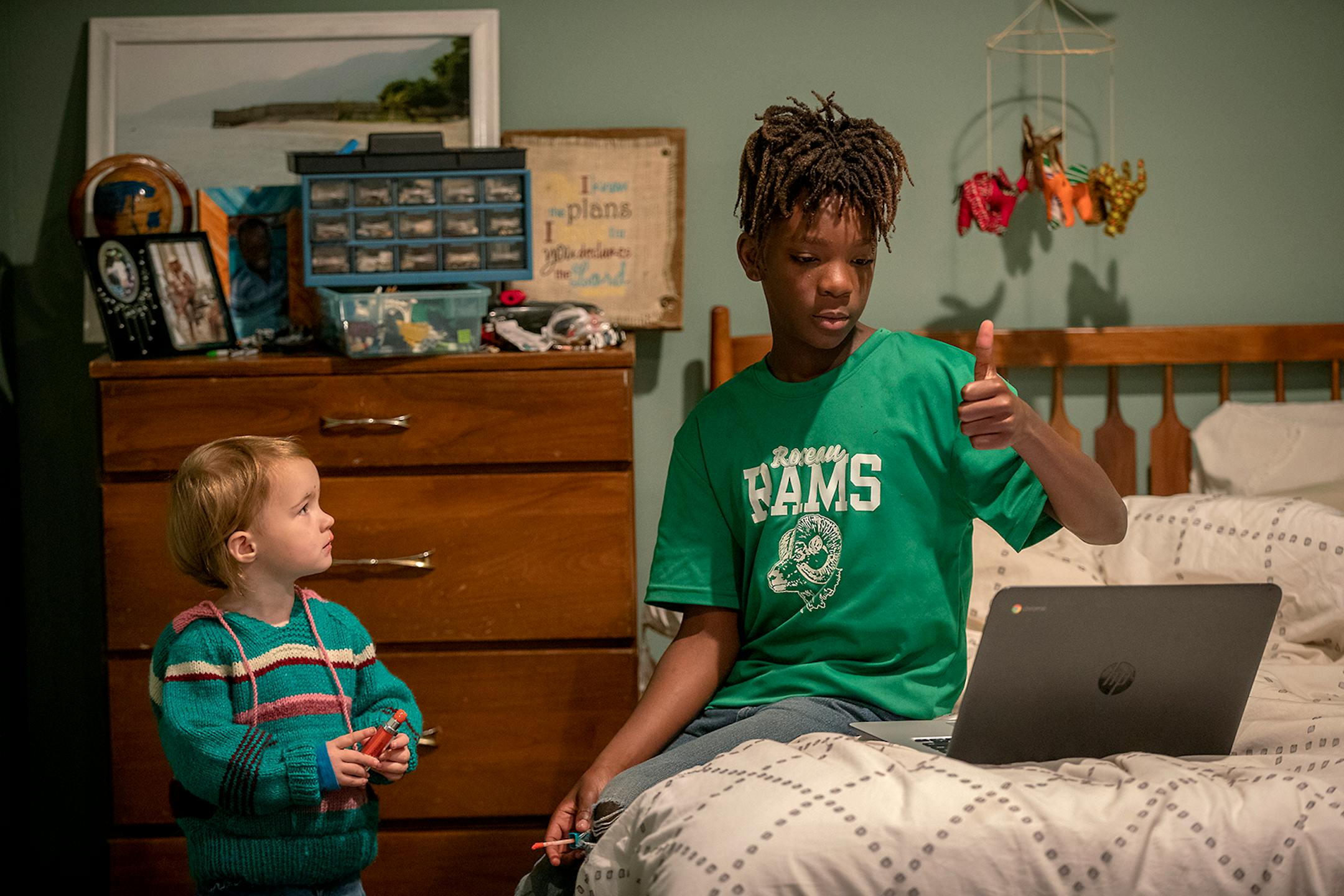 Nelson Lundquist, 11, worked on school and gave a thumbs-up to his teacher as his little sister Verabeth, 2, vied for his attention at their Brooklyn Park home, Tuesday, September 29, 2020.