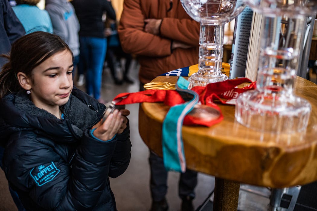 Young skier Maren Murphy, 8, looked at the Olympic medals of Jesse Diggins during an event at Theodore Wirth Park in Minneapolis in April 2023 to promote the Loppet Cup, a 2024 World Cup event at Wirth this weekend.