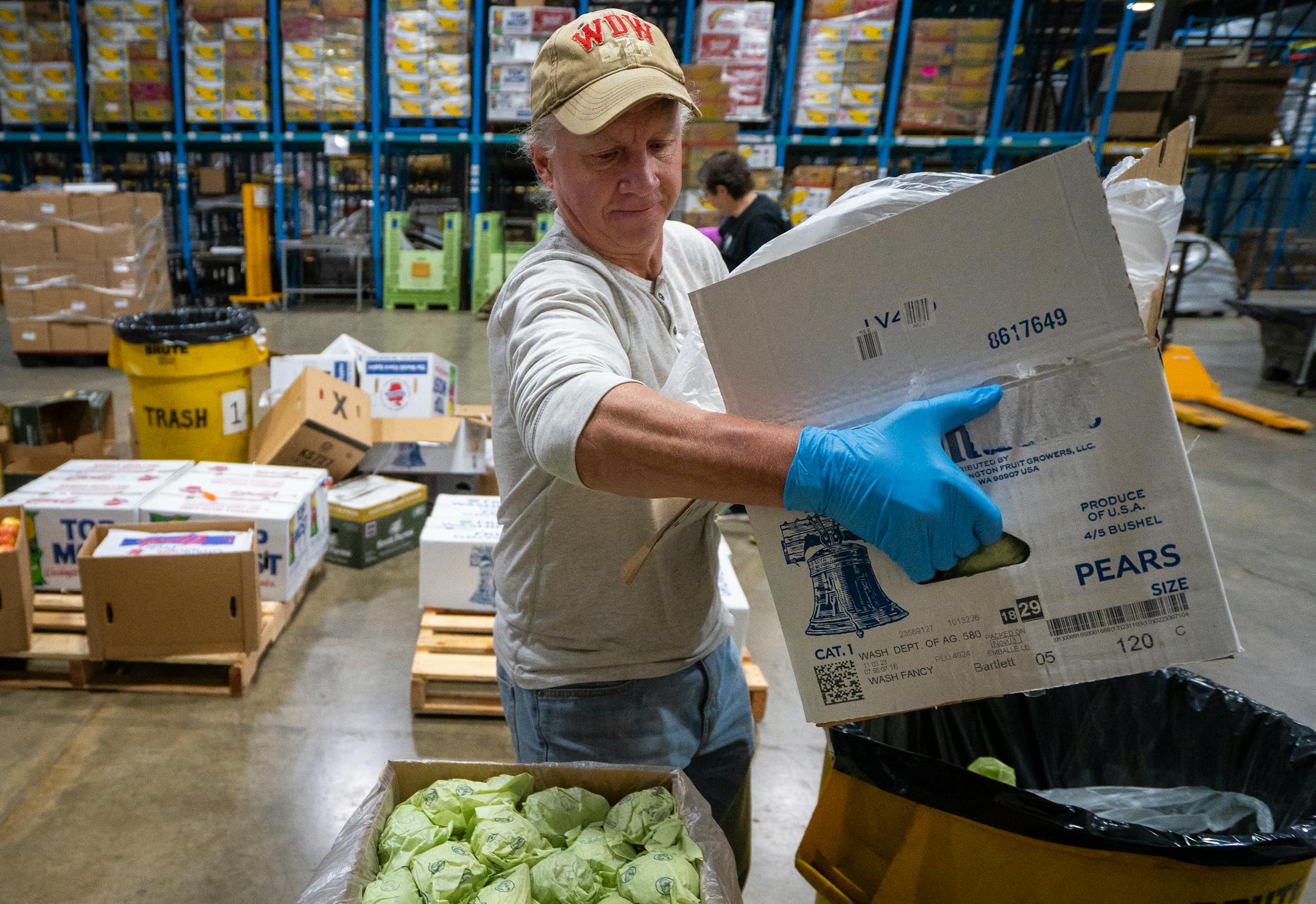 Brian Anderson, a volunteer with the Food Group, brings a fresh box of pears to the factory line.
