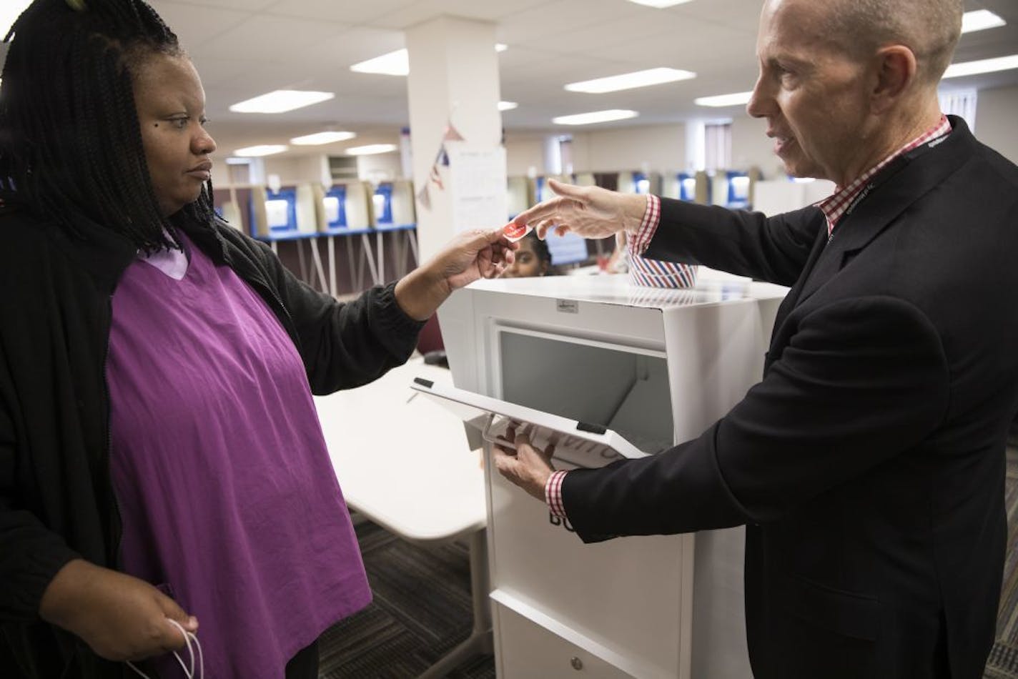 Voter Arnisha Jones gets an "I Voted" sticker from election judge Greg Munson after voting.