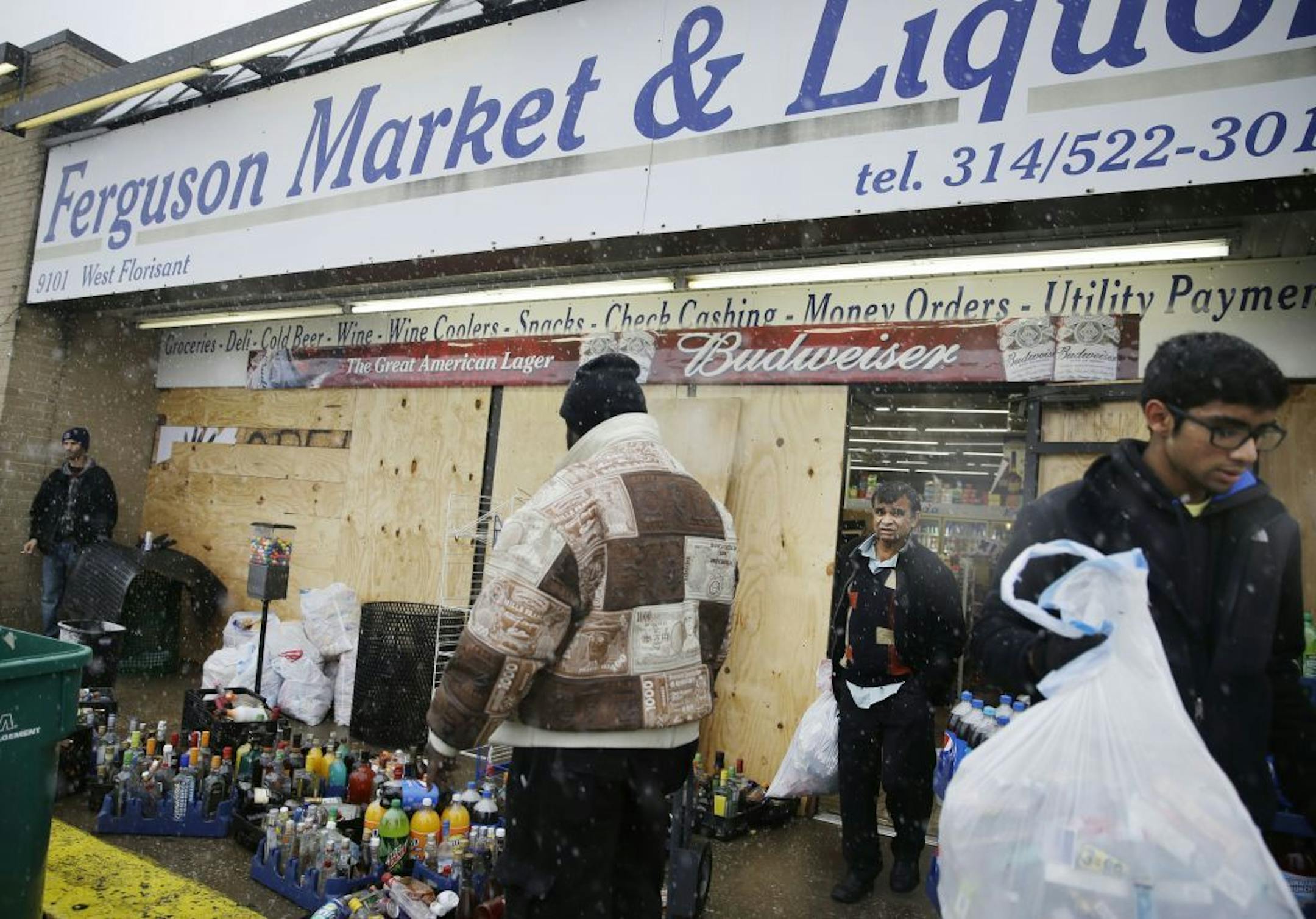 Kush Patel, right, carries out bags of merchandise while helping his uncle Andy Patel, rear, clean up the looting damage from Monday's riots at his store, Ferguson Market and Liquor, Wednesday, Nov. 26, 2014, in Ferguson, Mo. A grand jury's decision not to indict a police officer in the shooting death of an unarmed 18-year-old has stoked passions nationwide, triggering debates over the relations between black communities and law enforcement.