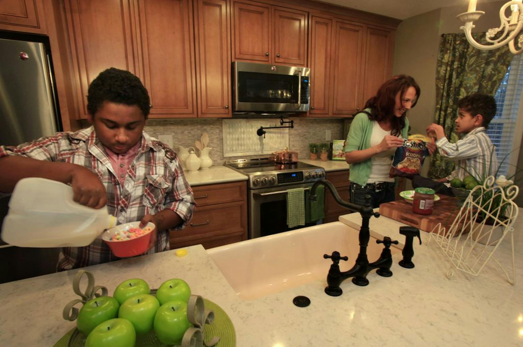 Tara Canfield helps Brandon (stripped shirt in front of Tara) get a snack with Isaiah (left)helping himself to a bowl of cereal. Tara Canfield is the singe mom of 8 kids and she was given a kitchen makeover by the Rachael Ray show. New Brighton, MN on December 6, 2012.
