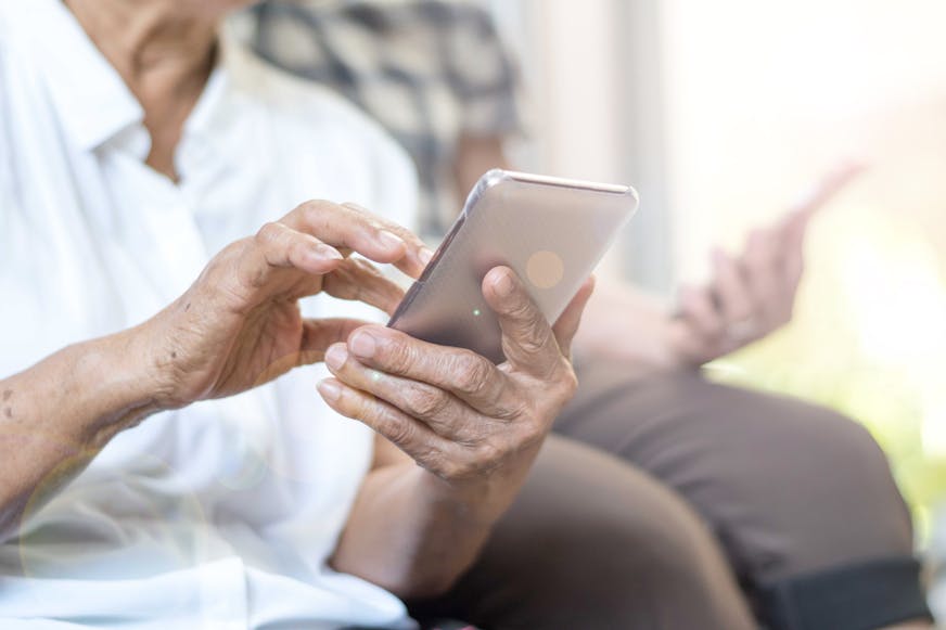 Two elderly people use smartphones in their home