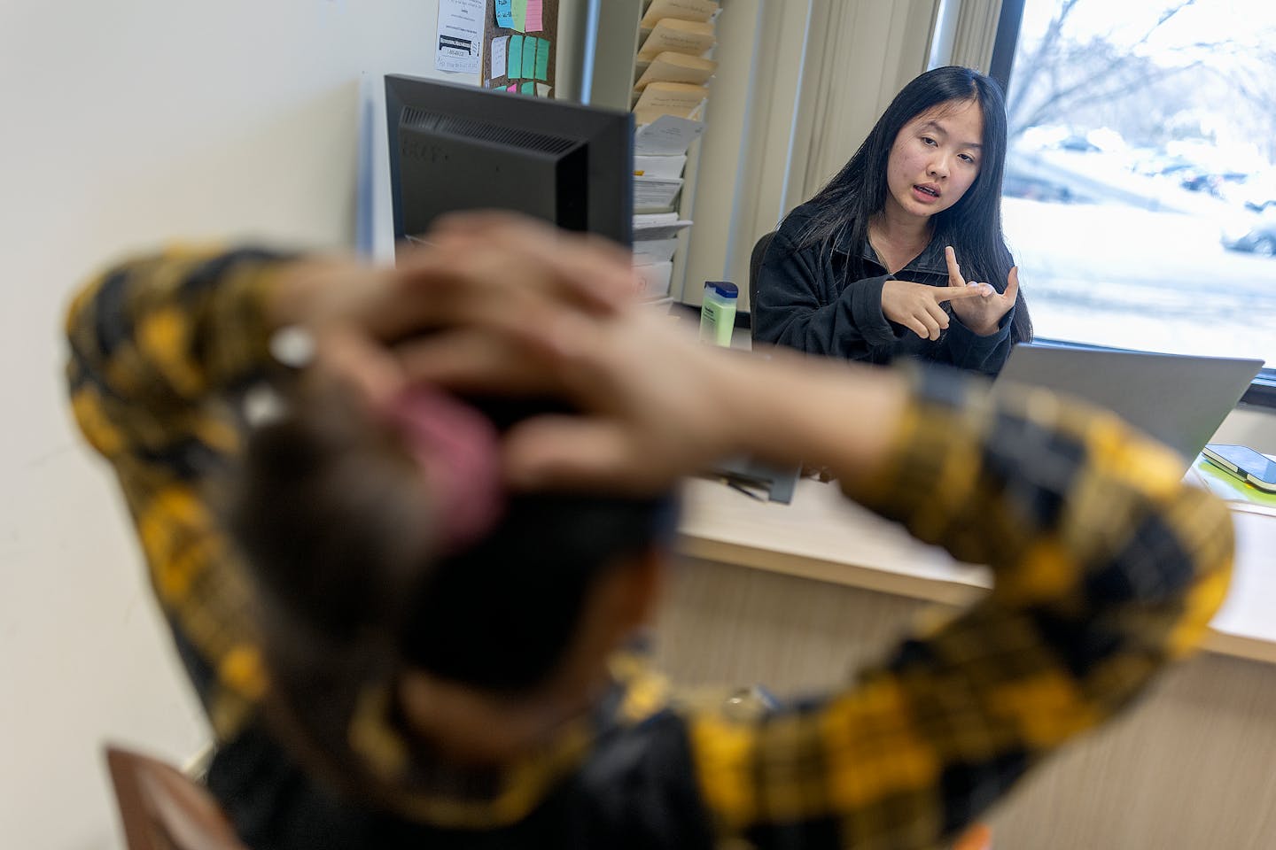 Toe Leh, a case manager with the Karen Organization of Minnesota, works with clients in her office in Roseville on Friday.