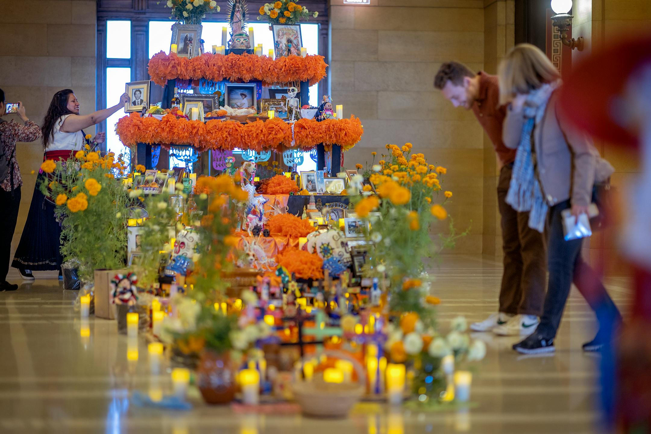 Artist Monica Vega, left, places a photo on the first ever "Altar de Muertos" or community altar for Days of the Dead  at the Minnesota State Capitol.