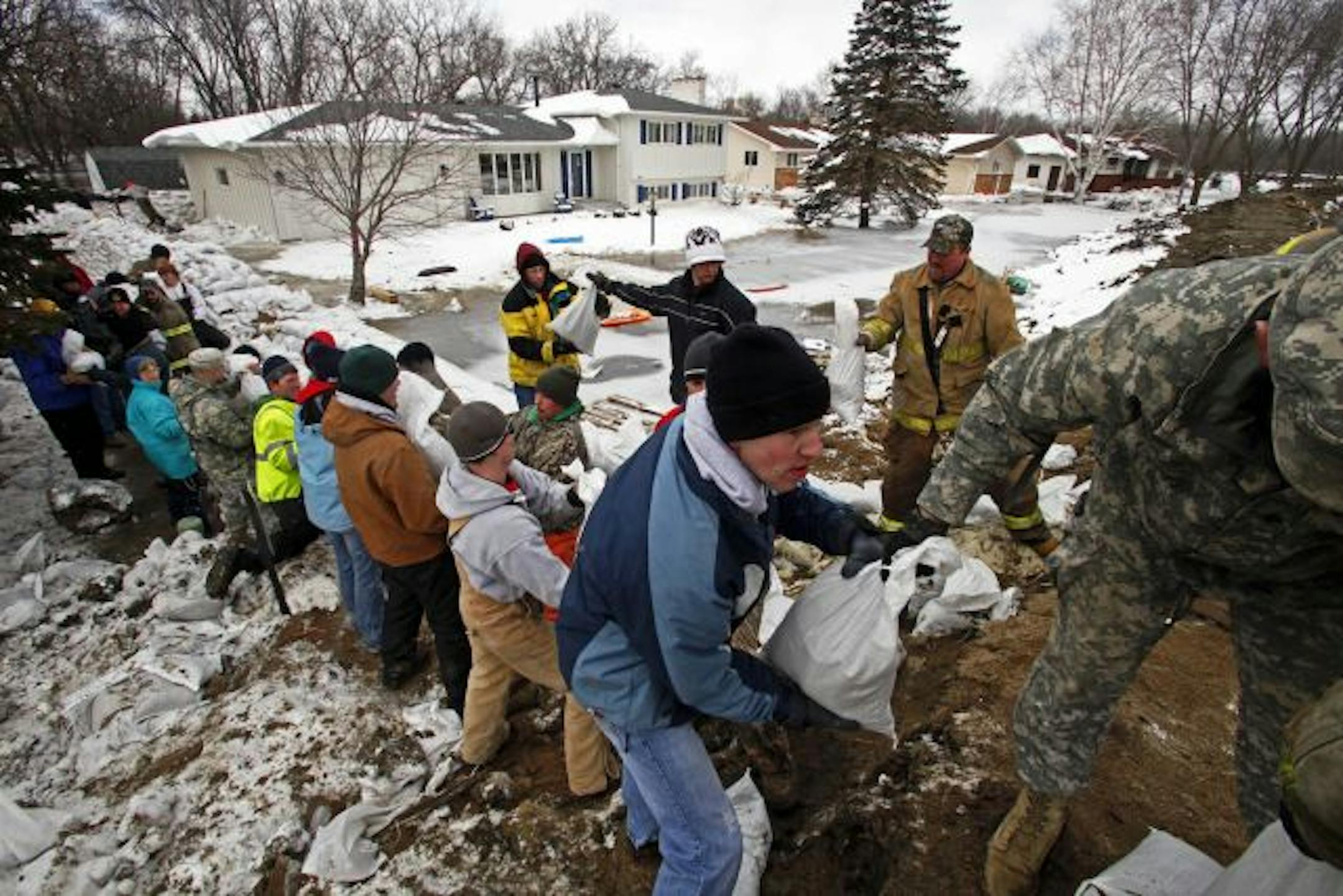 Volunteers help shore up a line of sandbags in the Horn Park area of Moorhead where houses in the background have been flooded and the residents evacuated last night. The flooding was due to a breach in a sand bag levee.