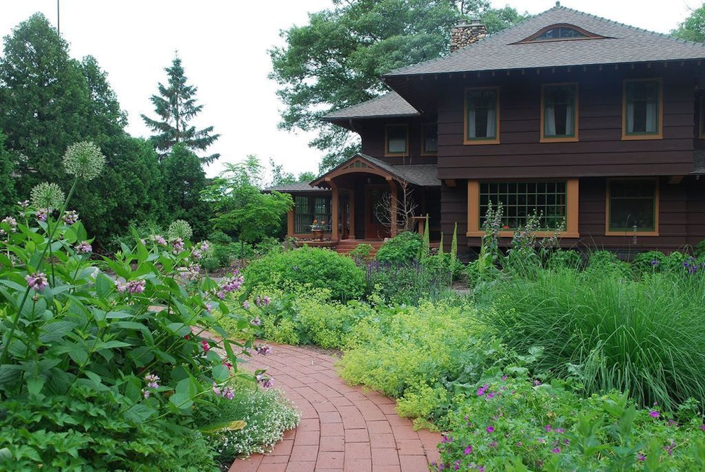 Perennials and grasses shaped by a fieldstone wall and brick pathway feel like they've always graced the front entry of the century-old Craftsman.