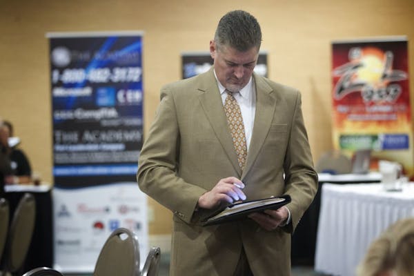 In this Friday, Nov. 30, 2012, photo, an unidentified job seeker uses his iPad to help fill out job applications at the Fort Lauderdale Career Fair, i