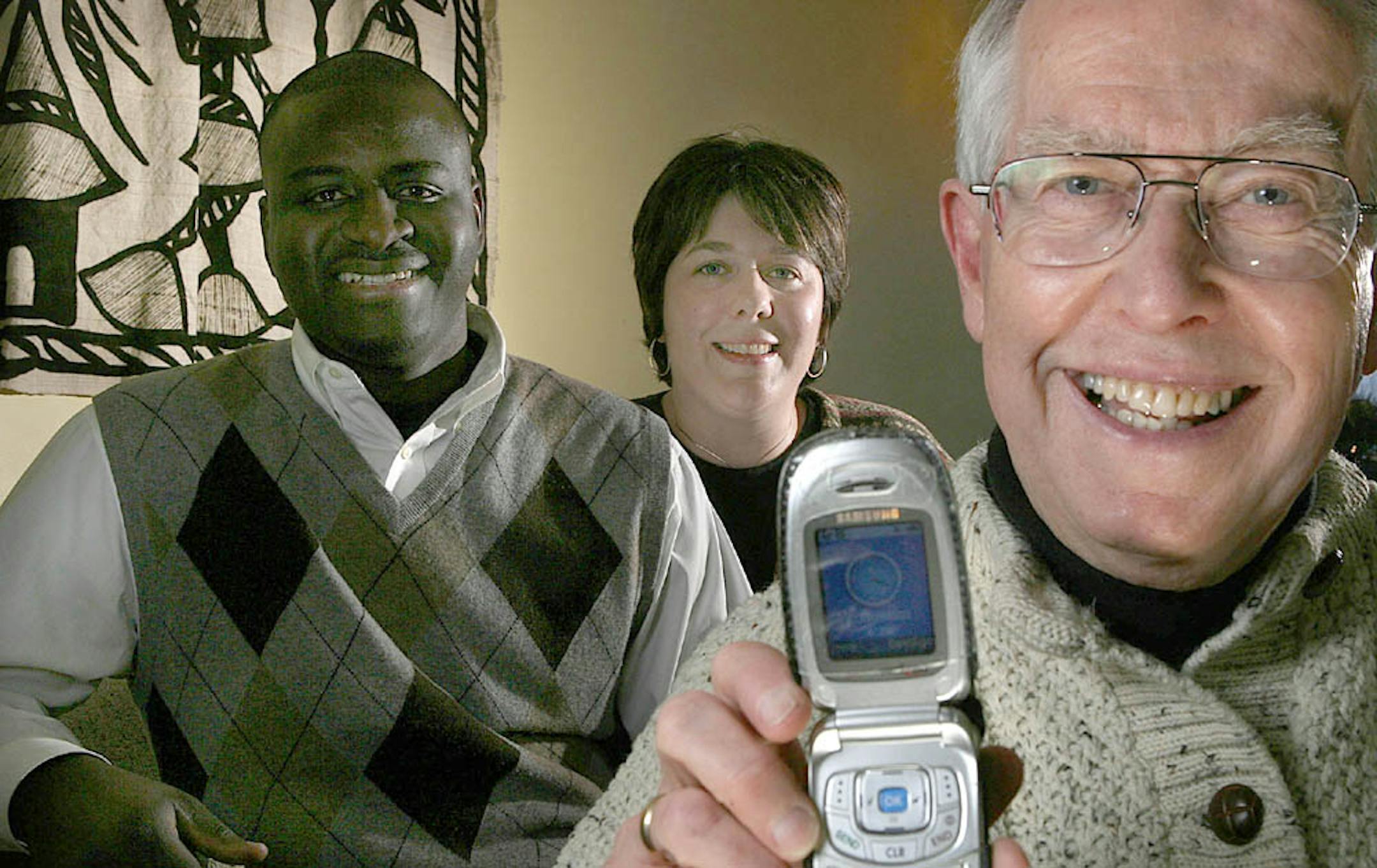 Retired psychiatrist Dick Anderson, 73, displayed the cell phone he lost that was later returned to him by good Samaritan Bocar Kane, left, and his wife, Alison.