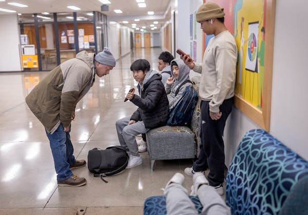 St. Paul Police Officer Jim Lee checks in with Karen students at Humboldt High School before taking them to the Urban Village in St. Paul on March 26.