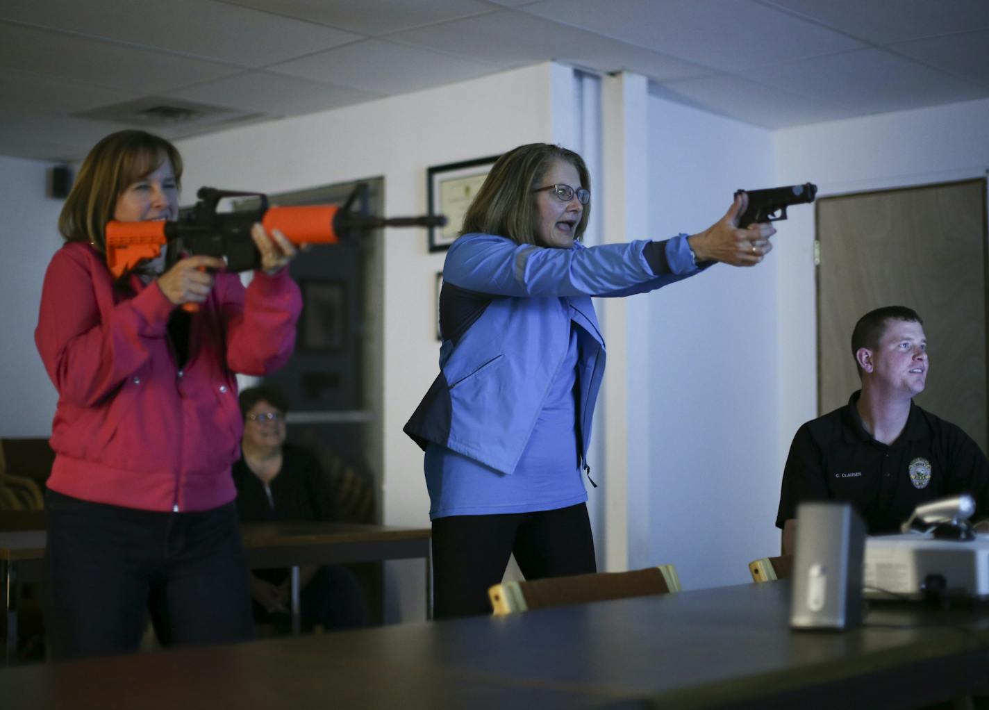 Kathleen Cates and Judy Hayes participated in an interactive shoot/don't shoot video exercise directed by Eagan Police Officer Chad Clausen, right, Tuesday night at the Flint Hills Training Center. ] JEFF WHEELER &#xef; jeff.wheeler@startribune.com Teachers from Dakota County schools have been getting a crash course in public safety from Rosemount, Apple Valley, and Eagan police trainers during the four session Teacher Police Academy. It's a twist on the popular citizen's police academy format,