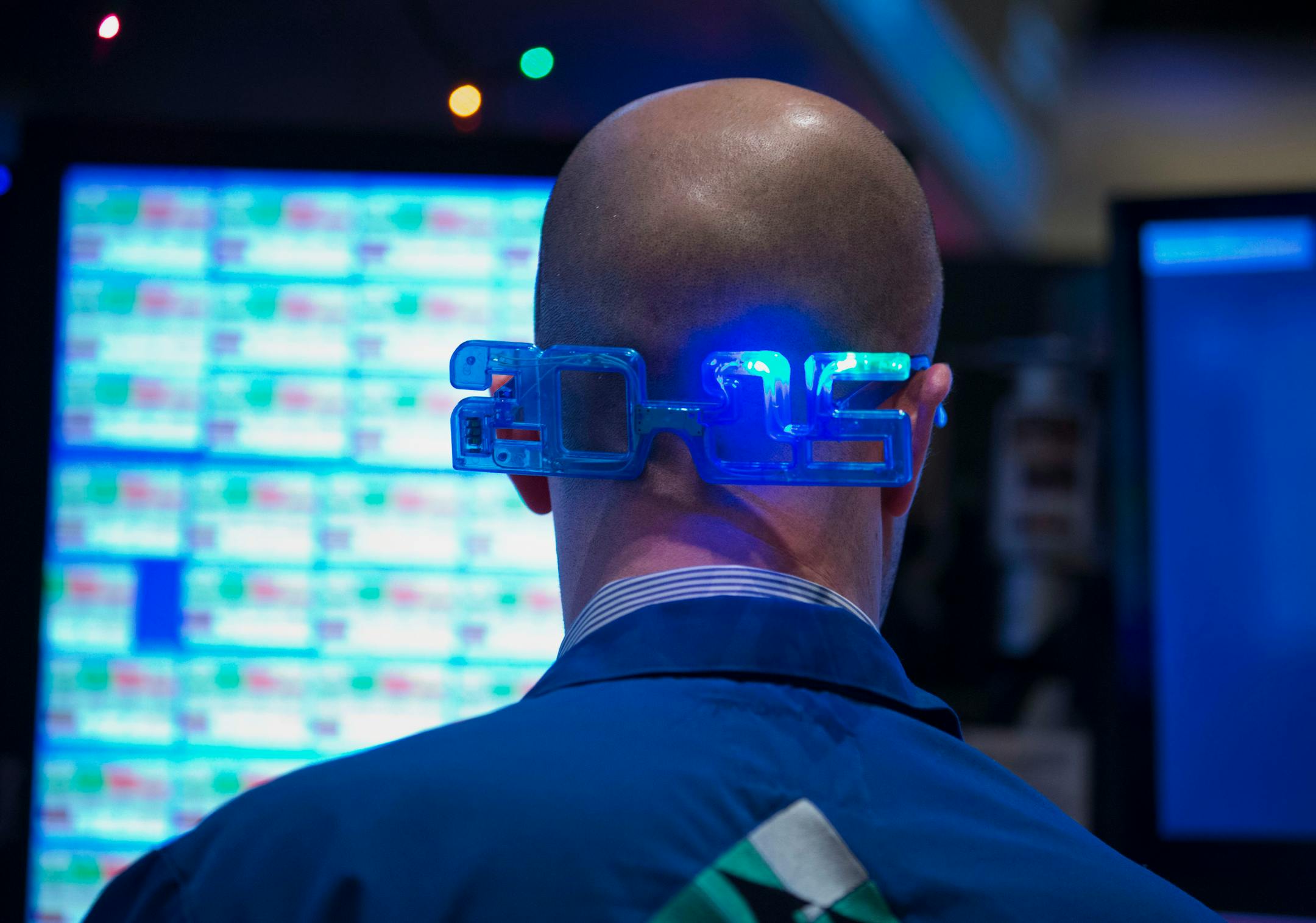 A trader works while wearing 2015 glasses on the floor of the New York Stock Exchange (NYSE) in New York, U.S., on Wednesday, Dec. 31, 2014. U.S. stocks were little changed on the last trading day of a year that capped the biggest bull market since the 1990s. Photographer: Jin Lee/Bloomberg