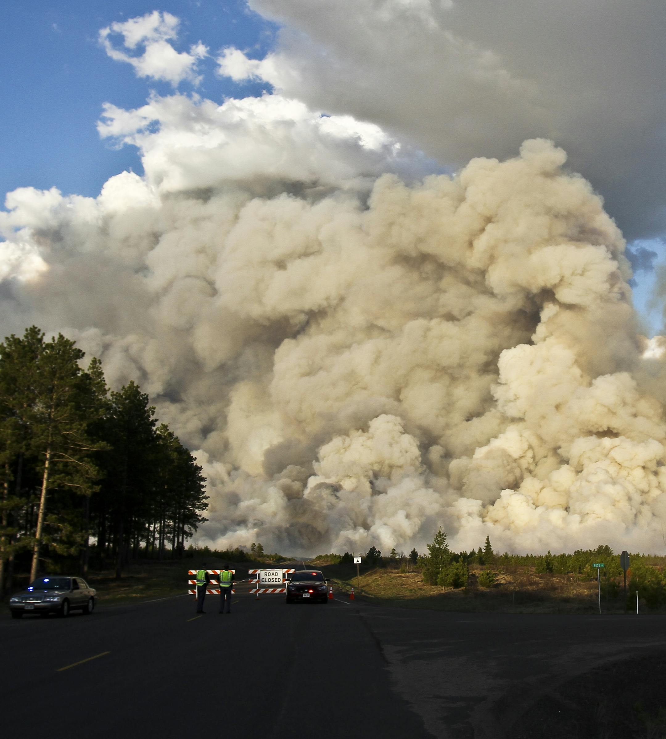 A smoke plume rises high above a road block at the intersection of County A and Ross Road east of Solon Springs, Wis., Tuesday, May 14, 2013. Crews from Wisconsin and Minnesota were trying to control a rapidly growing wildfire in northwestern Wisconsin that forced evacuations of the sparsely populated area. Several structures were destroyed in a mostly rural and wooded area east of Solon Springs as the forest fire grew to 9 square miles, the Wisconsin Department of Natural Resources said. No inj