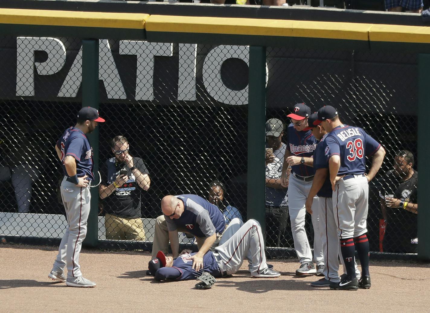 A member of the Minnesota Twins medical team looks over right fielder Taylor Motter after he fell to the ground after running into the right field wall support while trying to catch a deep fly ball from Chicago White Sox's Yoan Moncada during the sixth inning of a baseball game Thursday, June 28, 2018, in Chicago. (AP Photo/Charles Rex Arbogast)