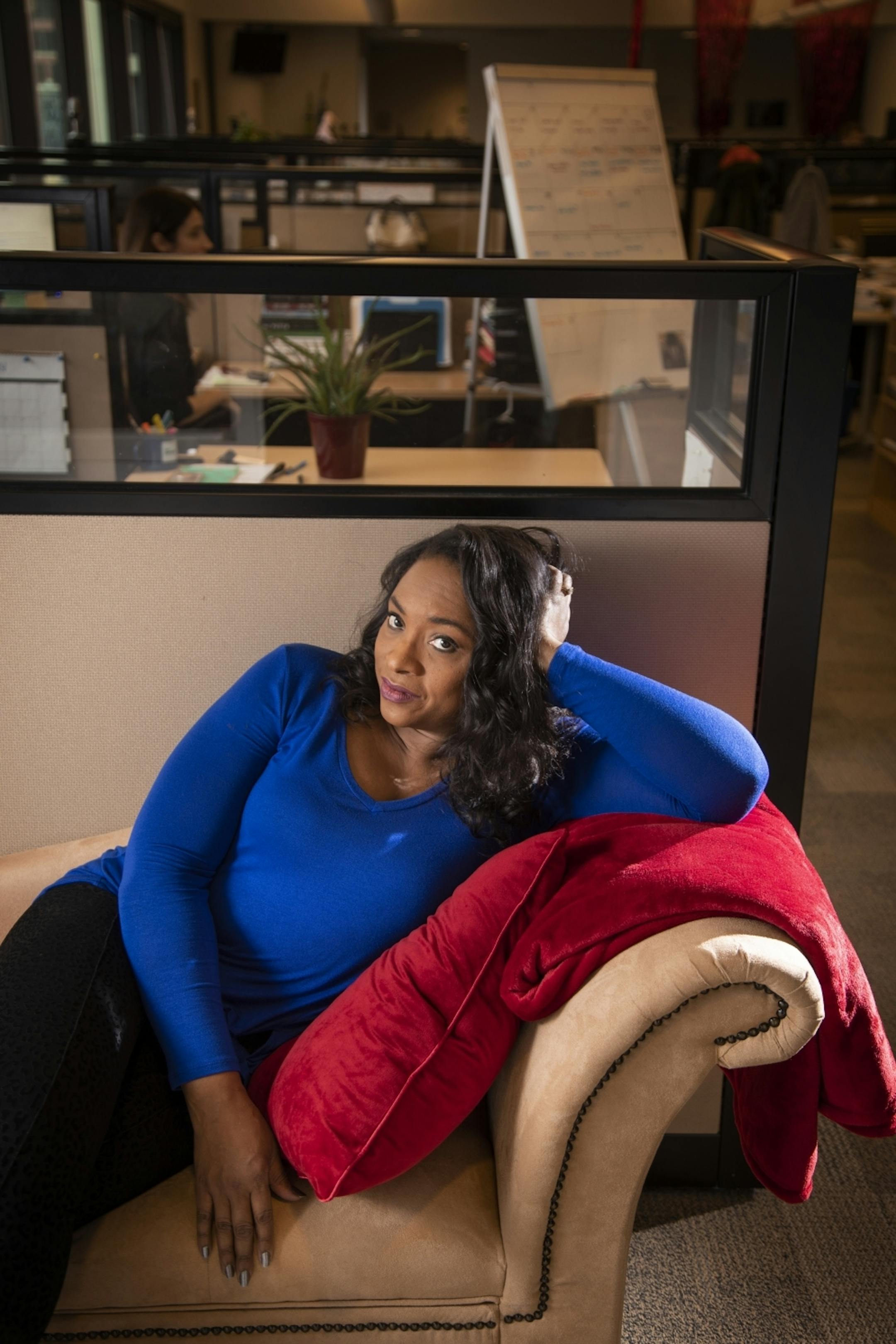 Angela Davis poses for a portrait on the new fainting couch near her desk in the MPR newsroom.