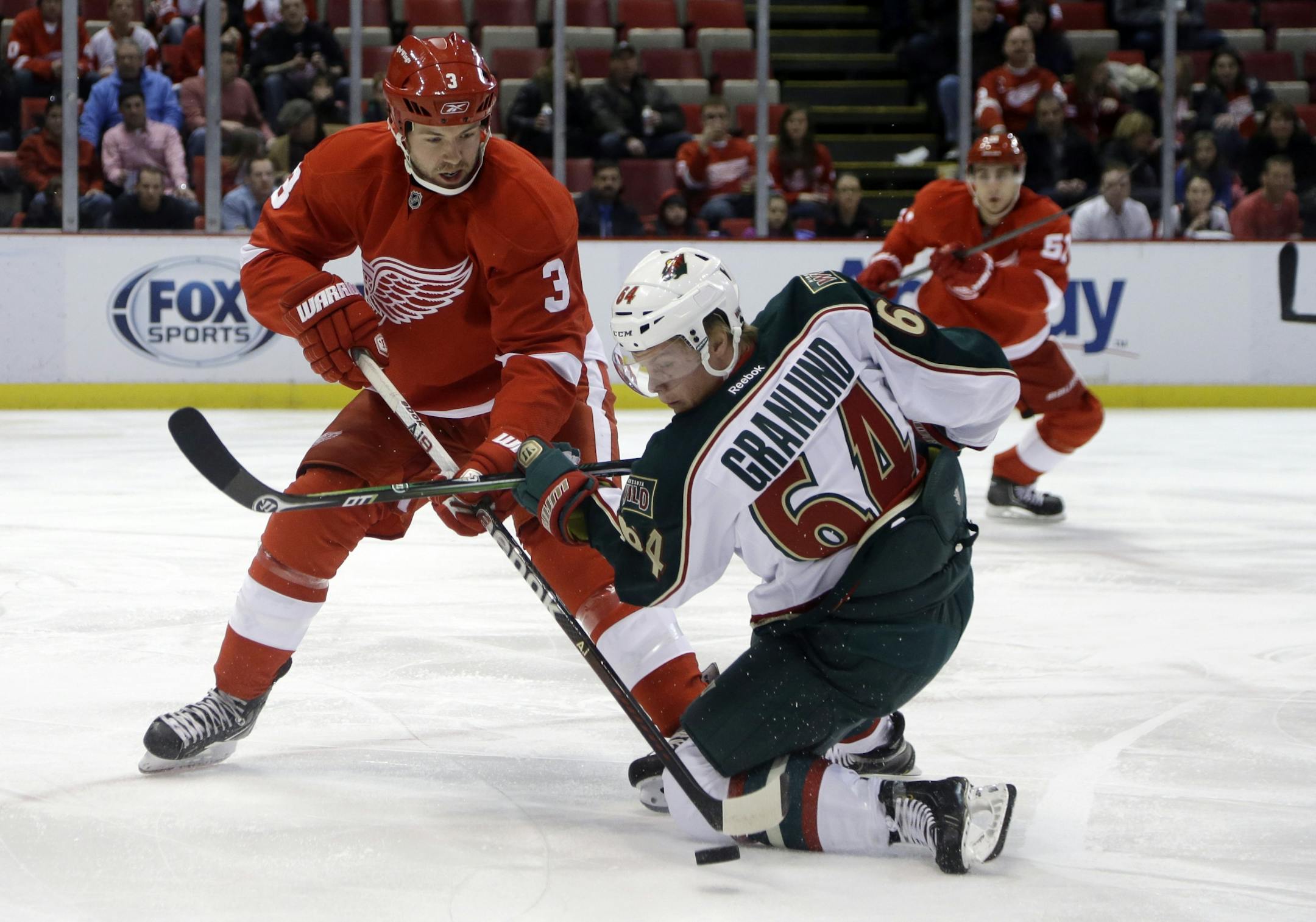 Detroit Red Wings defenseman Kent Huskins (3) and Minnesota Wild center Mikael Granlund (64) of Finland, battle for the puck during the first period of an NHL hockey game in Detroit, Jan. 25, 2013.