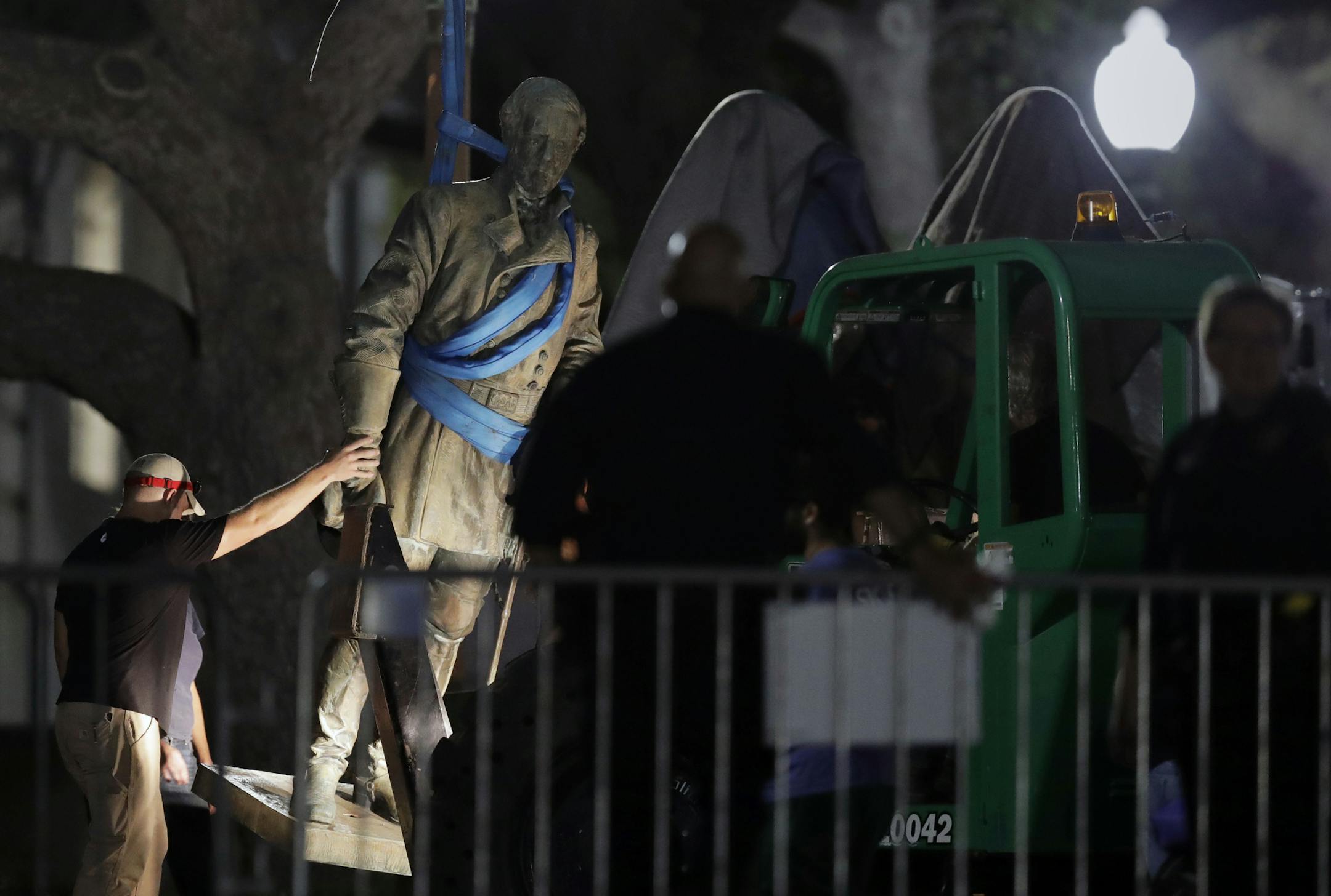 FILE - In this Aug. 21, 2017, file photo, a statue of Confederate Gen. Robert E. Lee is removed from the University of Texas campus in Austin, Texas. The University of Texas is being sued for removing four Confederate statues from the main area of is Austin campus. The Sons of Confederate Veterans filed the lawsuit three days after the statues were quickly taken down following an order from the university's president. The removals followed the deadly white supremacist rally in Virginia. The stat