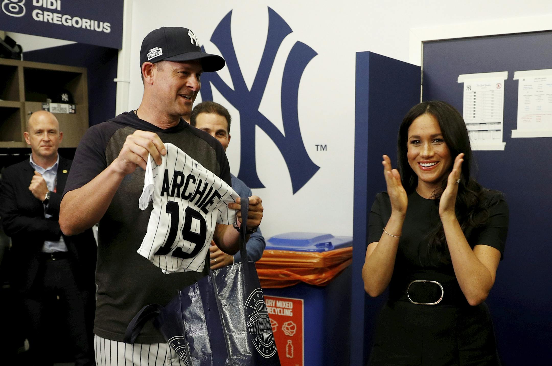 Britain's Prince Harry and Meghan, Duchess of Sussex receive a present for baby Archie as they meet players of the New York Yankees before a match against the Boston Red Sox in London, Saturday June 29, 2019. (Peter Nicholls/Pool via AP)