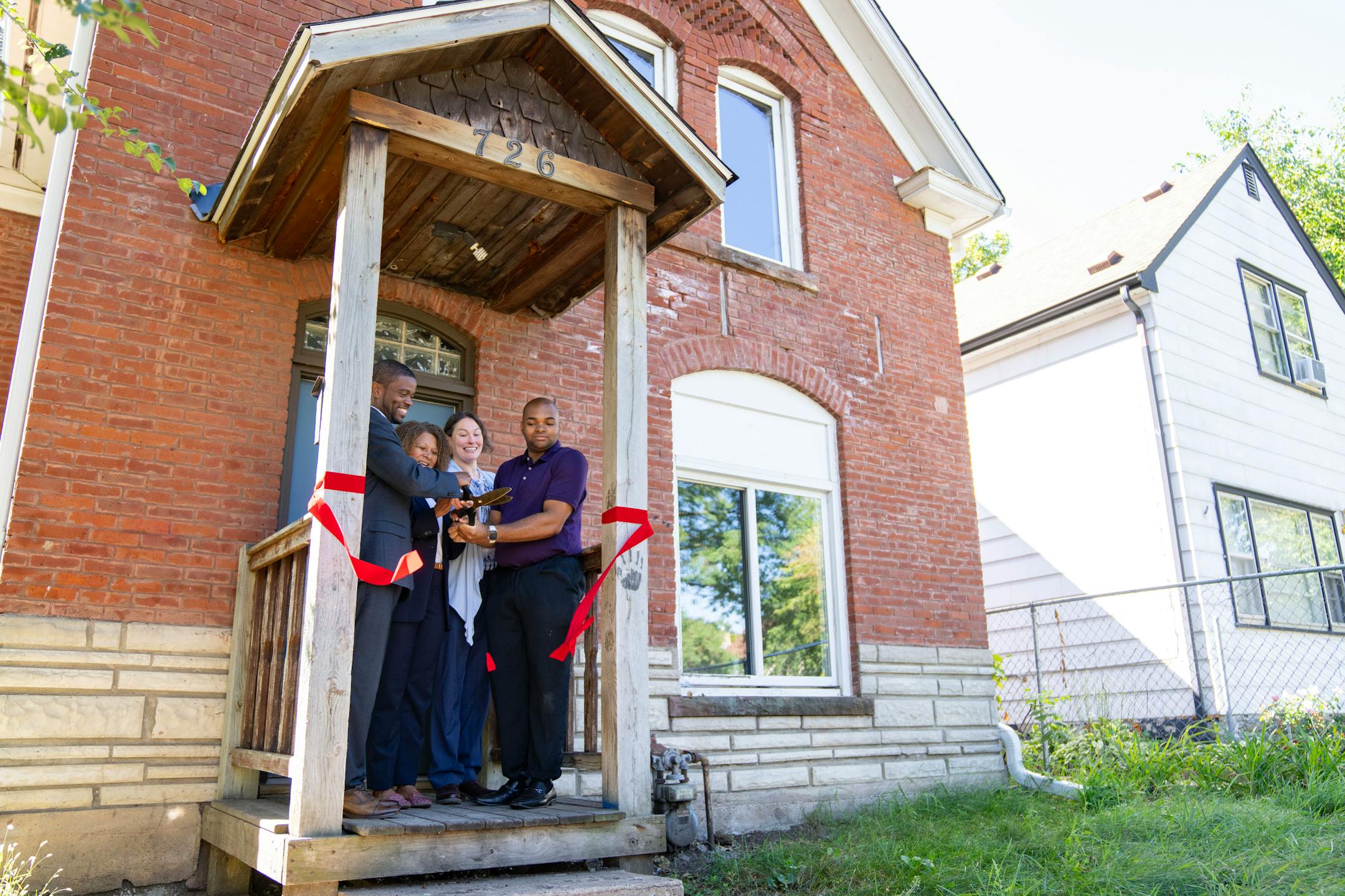 St. Paul Mayor Melvin Carter, Mikeya Griffin, Tara Beard and Anthony Bradford, left to right, cut a ceremonial ribbon Wednesday, Sep. 12, 2023, at Bradford's house in St. Paul, Minn. St. Paul's Inheritance Fund is a program designed to give Rondo neighborhood families displaced by the construction of I-94 forgivable loans to purchase or fix a house. Bradford is the first recipient as his great-grandfather was forced to move his family when the highway was built in the 1950s. ]