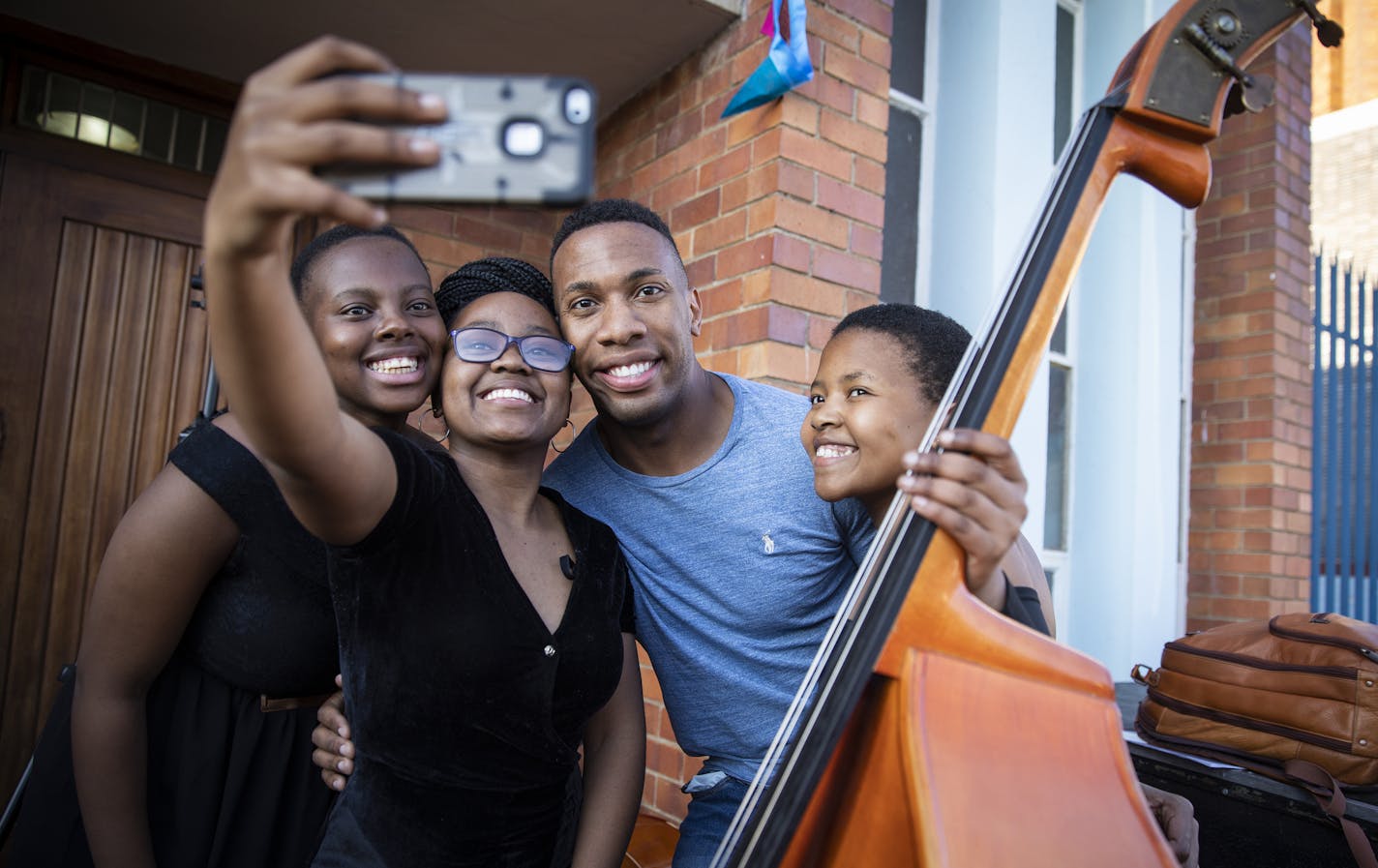 Roderick Cox poses for a photo with SANYO members Boitumelo Mtsatse, from left, Refilwe Moeketsane and Kamogelo Mothobi. ] LEILA NAVIDI &#xef; leila.navidi@startribune.com BACKGROUND INFORMATION: Minnesota Orchestra&#xed;s associate conductor Roderick Cox conducts a concert by the South African National Youth Orchestra (SANYO) at Brixton Kerk Church in Johannesburg, South Africa on Sunday, August 19, 2018.