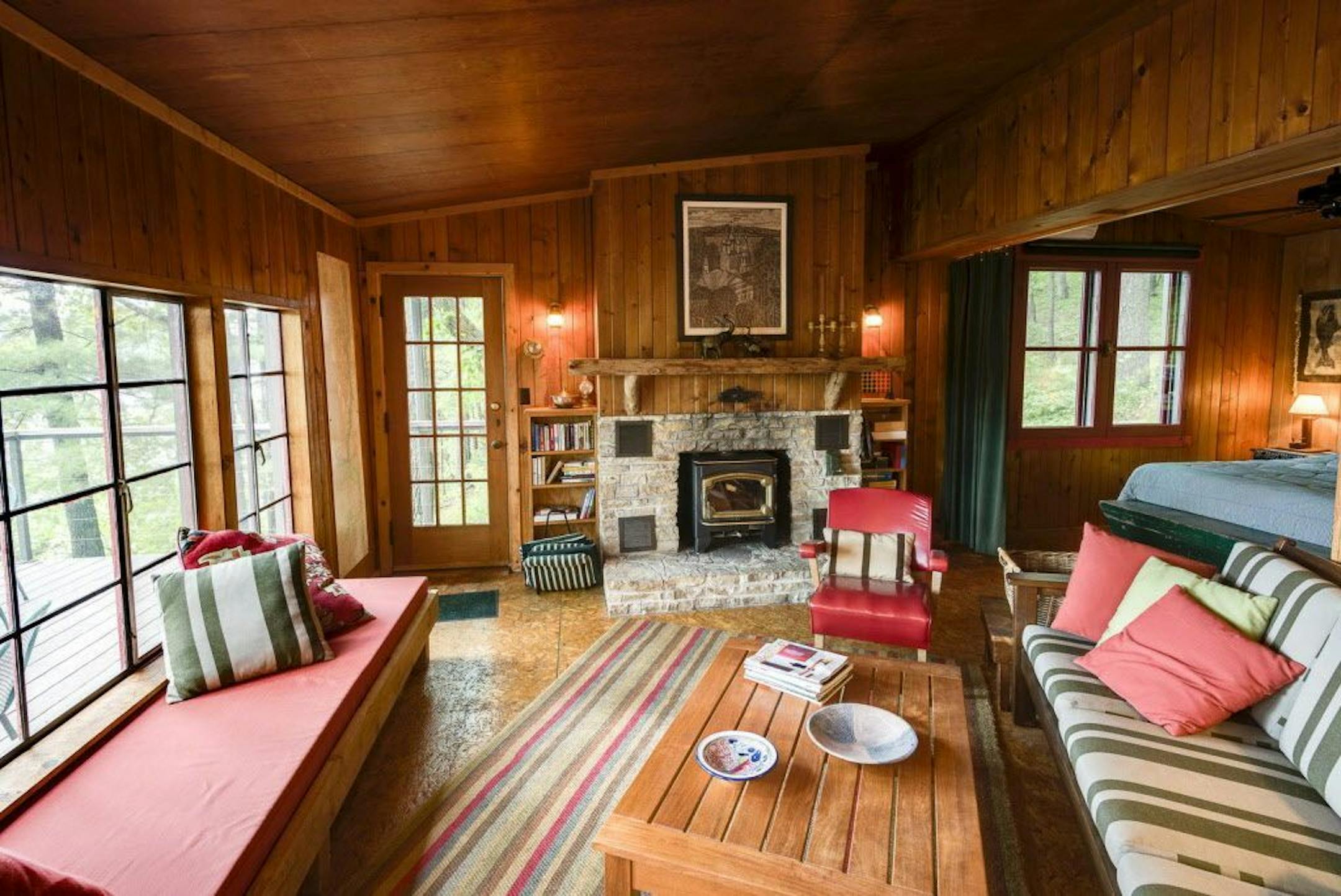 The main cabin has an open floor plan and a stone fireplace with wood-burning stove insert.