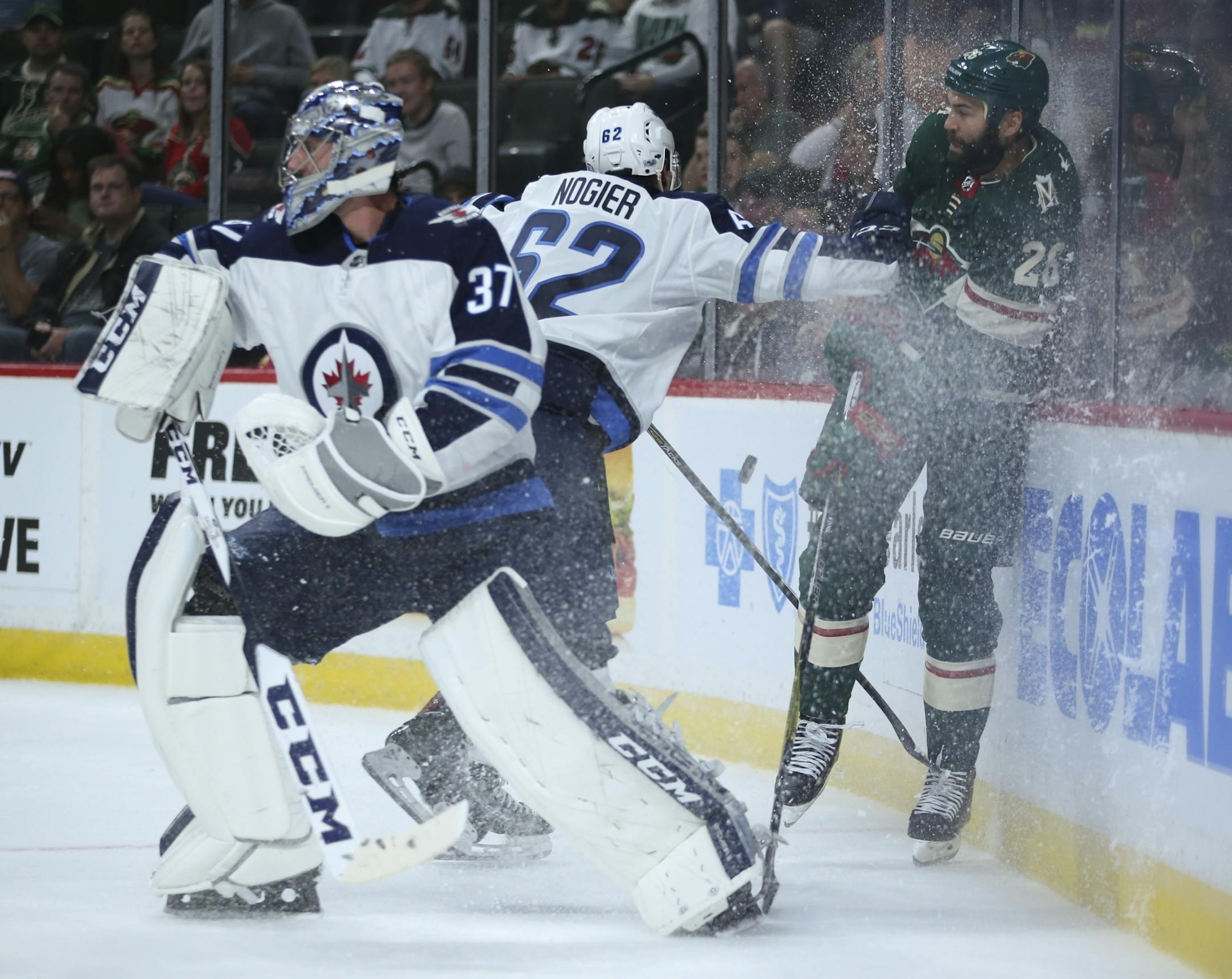 Minnesota Wild right wing Daniel Winnik (26) was checked into the boards by Winnipeg Jets defenseman Nelson Nogier (62) while trying to get to the puck in the first period last week at the X. Jets goalie Connor Hellebuyck (37) was in the foreground.