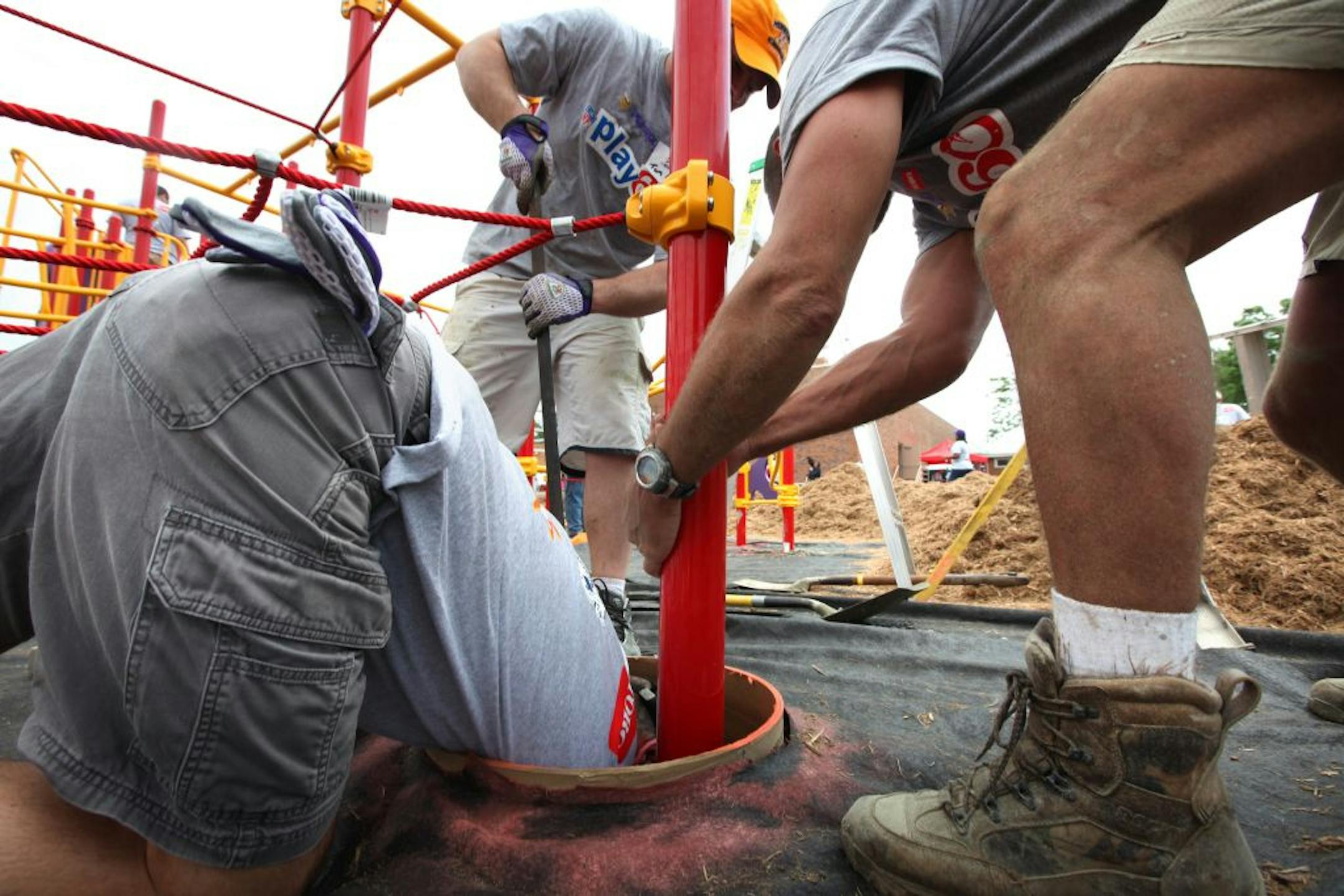 More than 250 volunteers, including more than 100 Vikings staff, coaches and former players, Toro employees and organizers from KaBOOM!—a national nonprofit organization that envisions a great place to play within walking distance of every child in America-will joined forces to build a new and safe playground at Northport Elementary School in Brooklyn Center Friday. (IN THIS PHOTO) Former Viking Scott Studwell (right) Doug Heiman with Toro (left) and Tom Hunkele (center) help set a post in concr