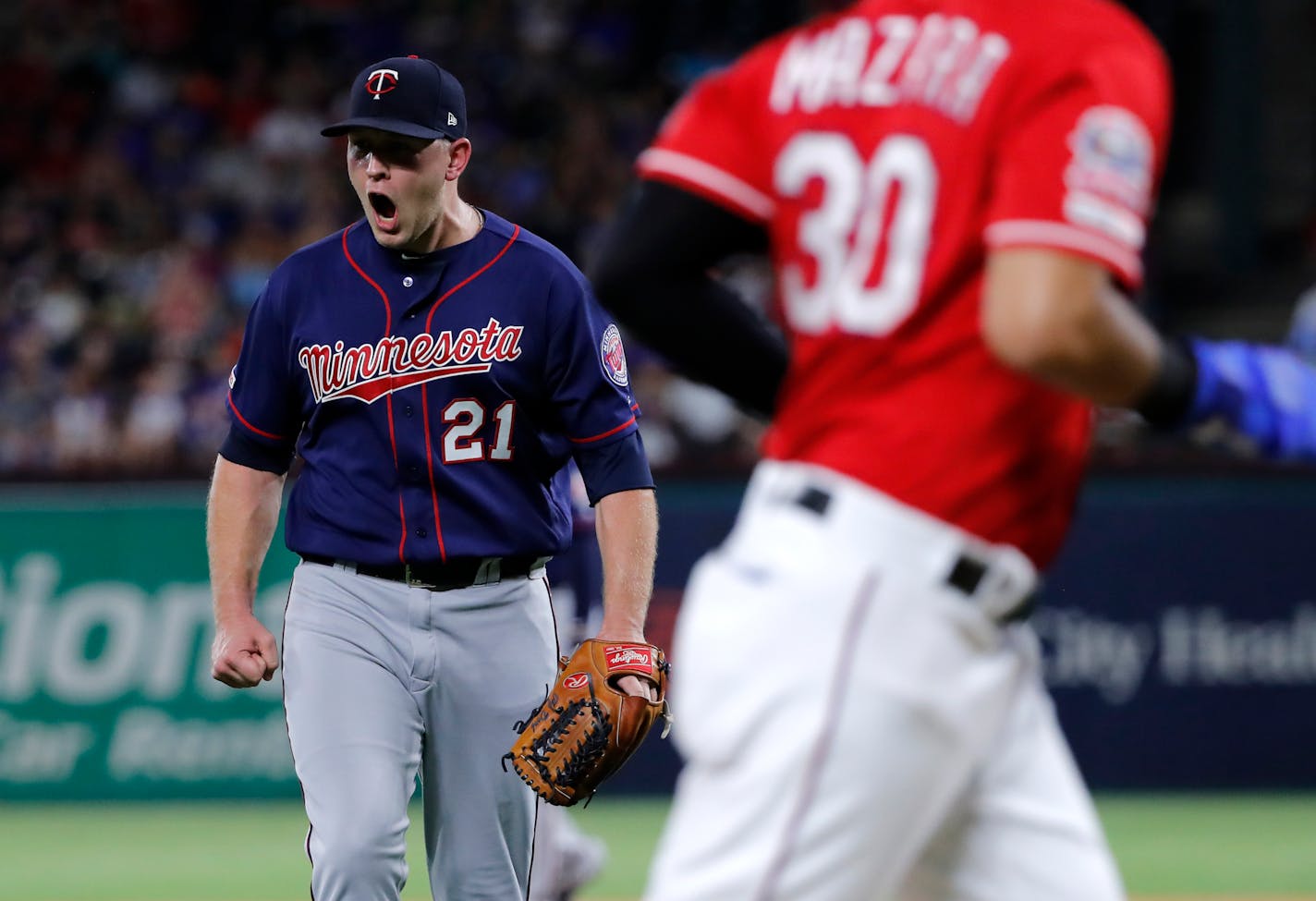 Texas Rangers' Nomar Mazara jogs to the dugout as Minnesota Twins relief pitcher Tyler Duffey (21) celebrates getting Isiah Kiner-Falefa to fly out with the bases loaded, ending the fifth inning of a baseball game in Arlington, Texas, Saturday, Aug. 17, 2019. (AP Photo/Tony Gutierrez)